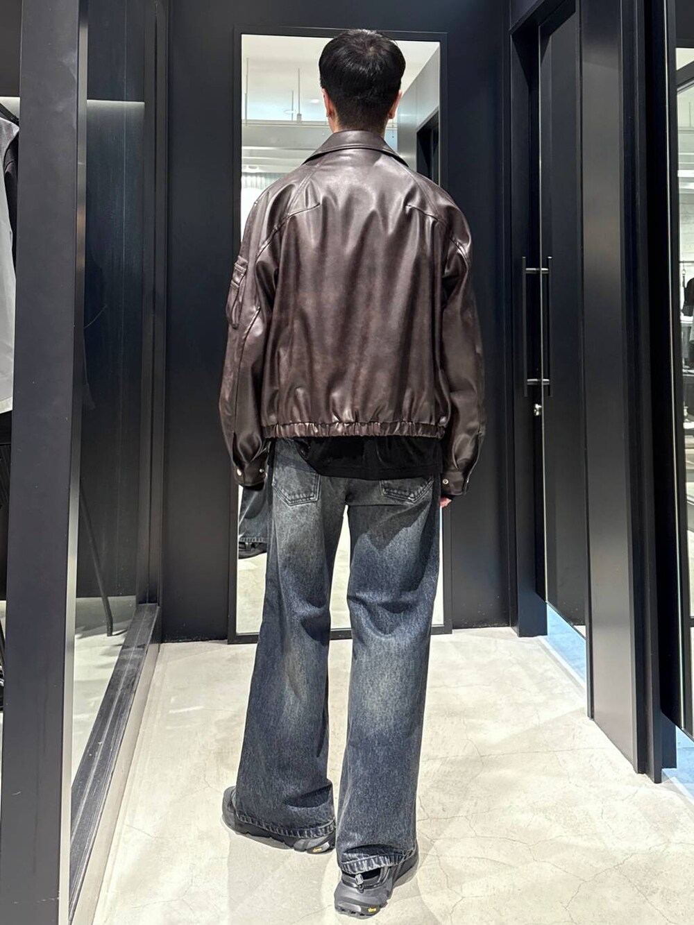 ブラック系のサンダル、ブラウン系のブルゾン、ブルー系のデニムパンツを着用したメンズの夏コーディネートの3枚目の写真