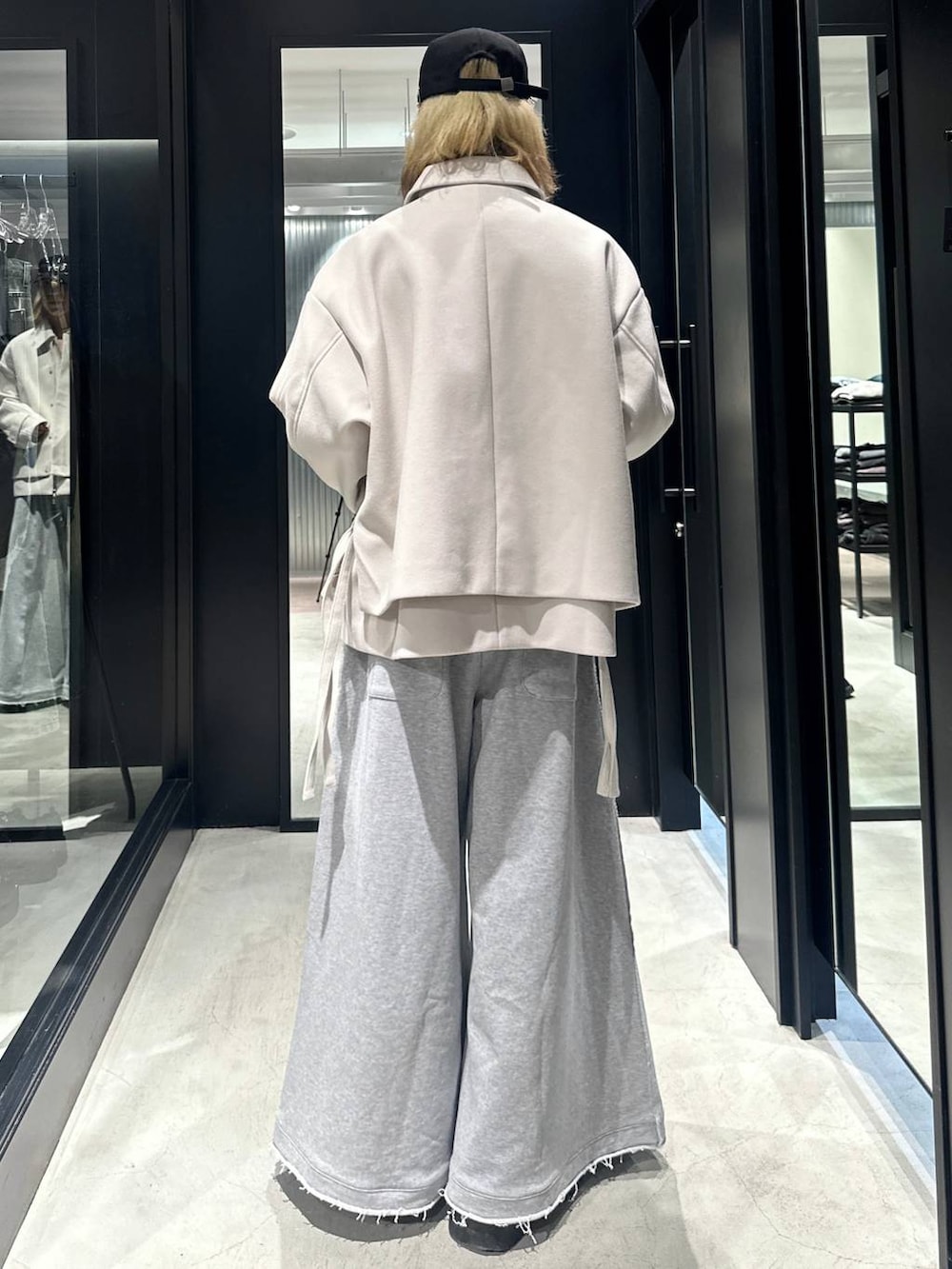 グレー系のスウェットパンツ、ホワイト系のブルゾン、ブラック系のキャップを着用したメンズの秋コーディネートの3枚目の写真