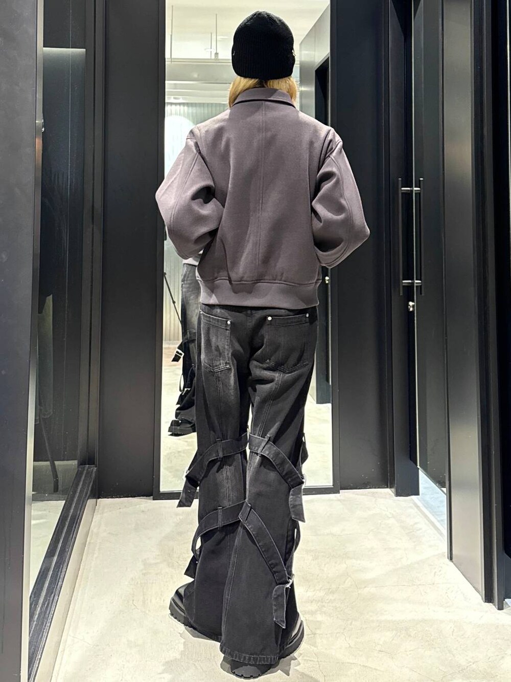 グレー系のブルゾン、ブラック系のドレスシューズ、ブラック系のデニムパンツを着用したメンズの秋コーディネートの3枚目の写真