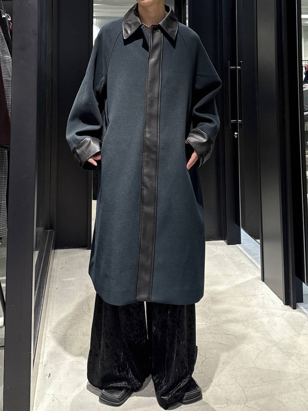 グリーン系のステンカラーコート、ブラック系のその他パンツ、ブラック系のスウェットを着用したメンズの秋コーディネートの3枚目の写真