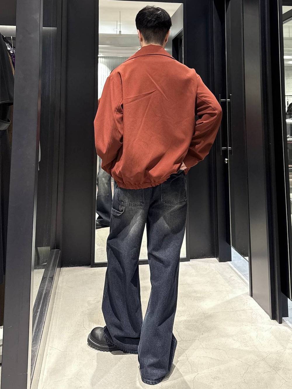 ブラック系のブーツ、ブルー系のデニムパンツ、オレンジ系のブルゾンを着用したメンズの秋コーディネートの3枚目の写真