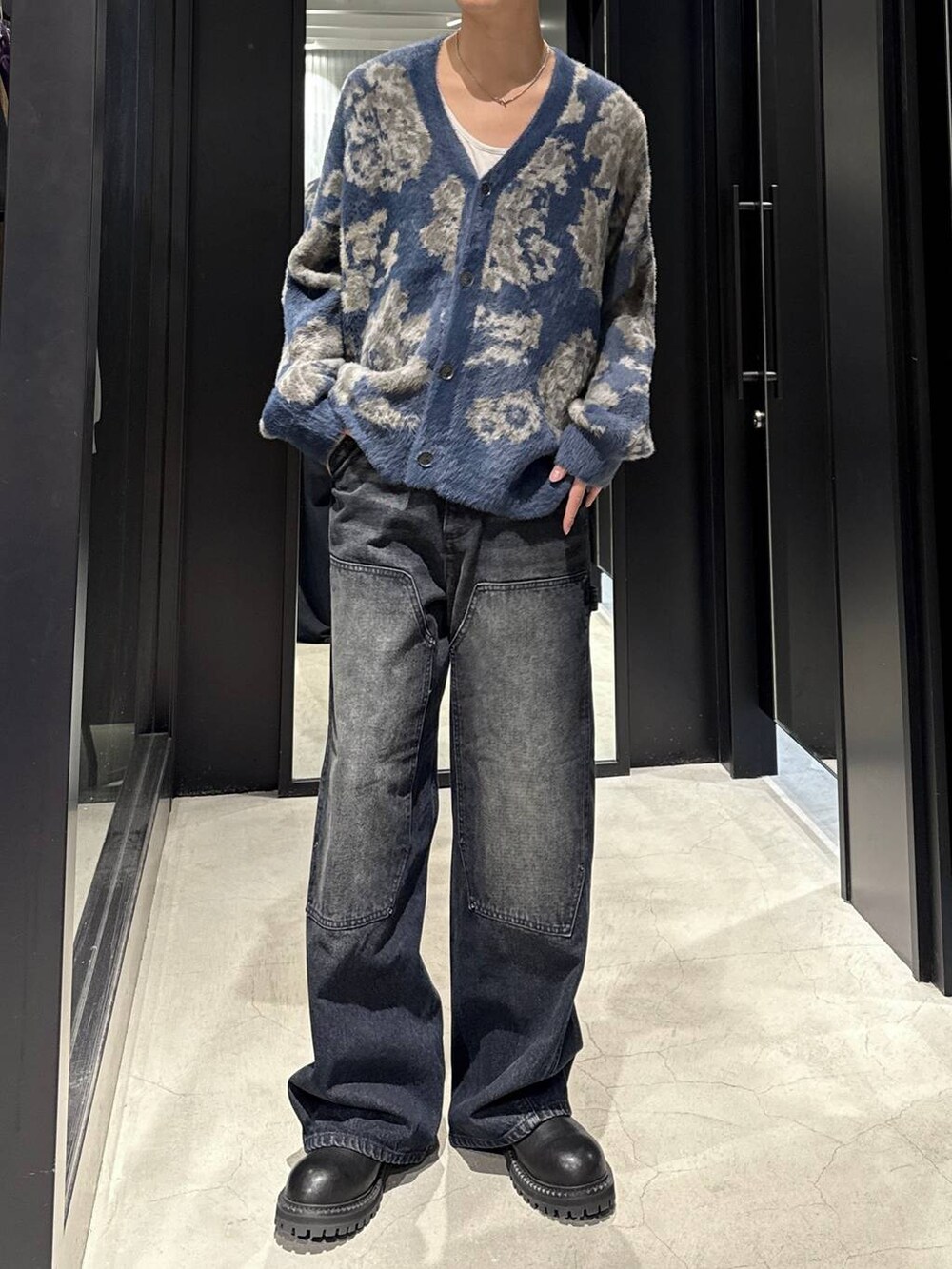 ブルー系のカーディガン/ボレロ、ブラック系のブーツ、ブルー系のデニムパンツを着用したメンズの秋コーディネートの4枚目の写真