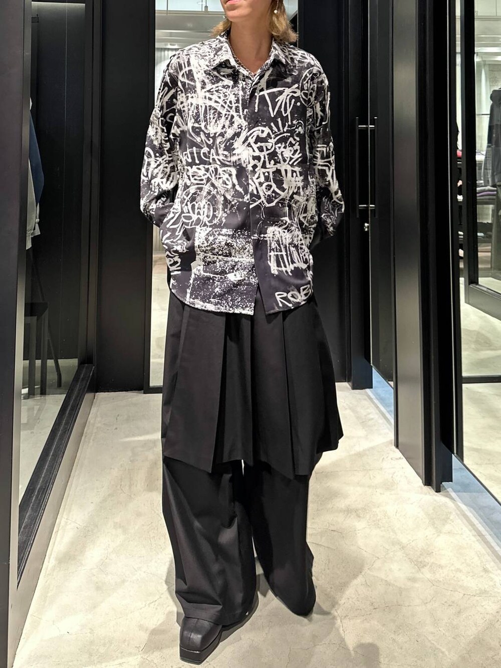 ブラック系のスラックス、ブラック系のブーツ、ブラック系のシャツ/ブラウスを着用したメンズの秋コーディネートの2枚目の写真