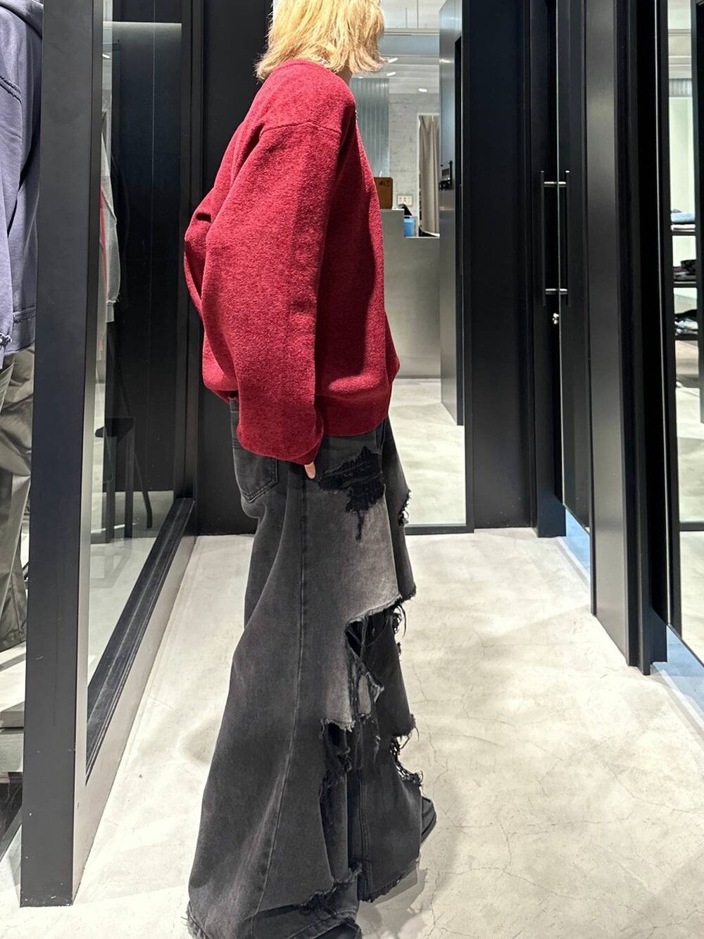 ブラック系のデニムパンツ、レッド系のニット/セーター、ブラック系のキャップを着用したメンズの秋コーディネートの3枚目の写真