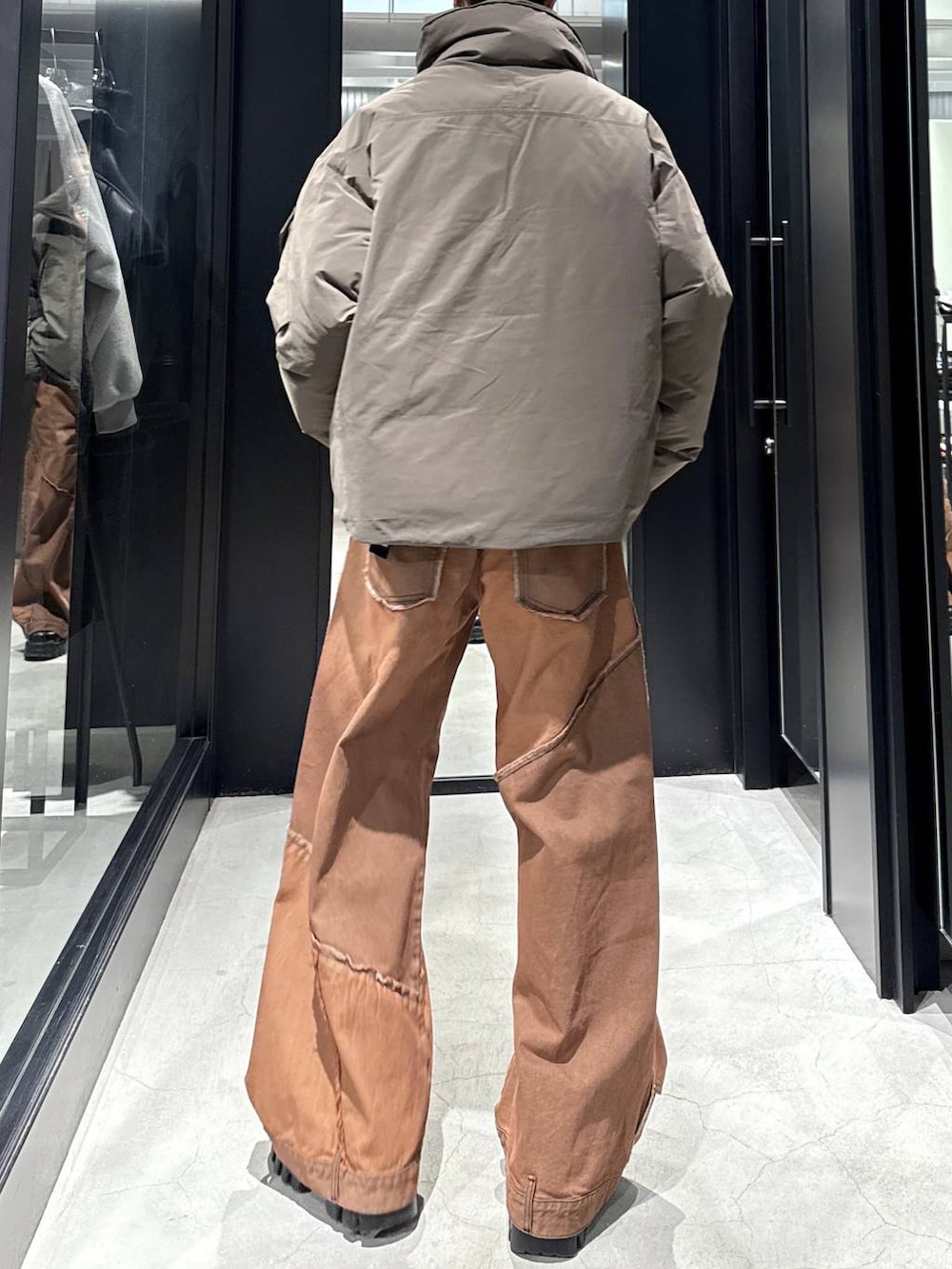 ブラウン系のダウンジャケット/コート、オレンジ系のデニムパンツ、シルバー系のネックレスを着用したメンズの冬コーディネートの4枚目の写真