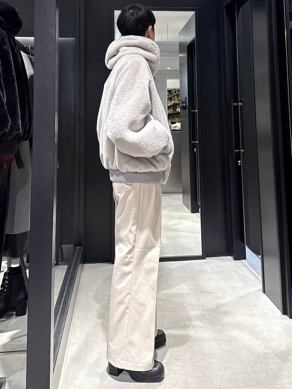 グレー系のブルゾン、ブラック系のブーツ、ホワイト系のデニムパンツを着用したメンズの冬コーディネートの2枚目の写真