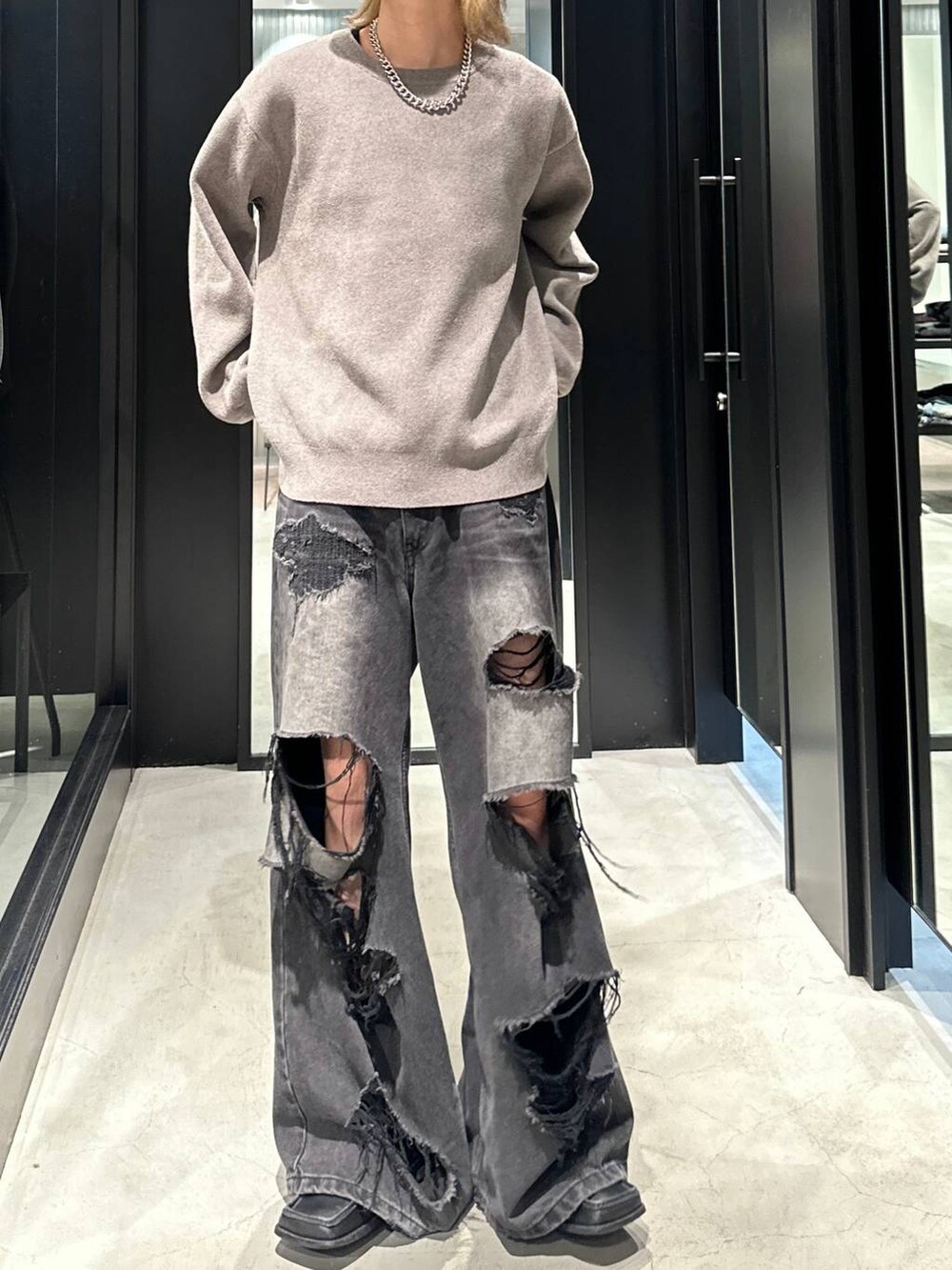 ブラック系のデニムパンツ、グレー系のニット/セーター、ブラック系のキャップを着用したメンズの秋コーディネートの4枚目の写真