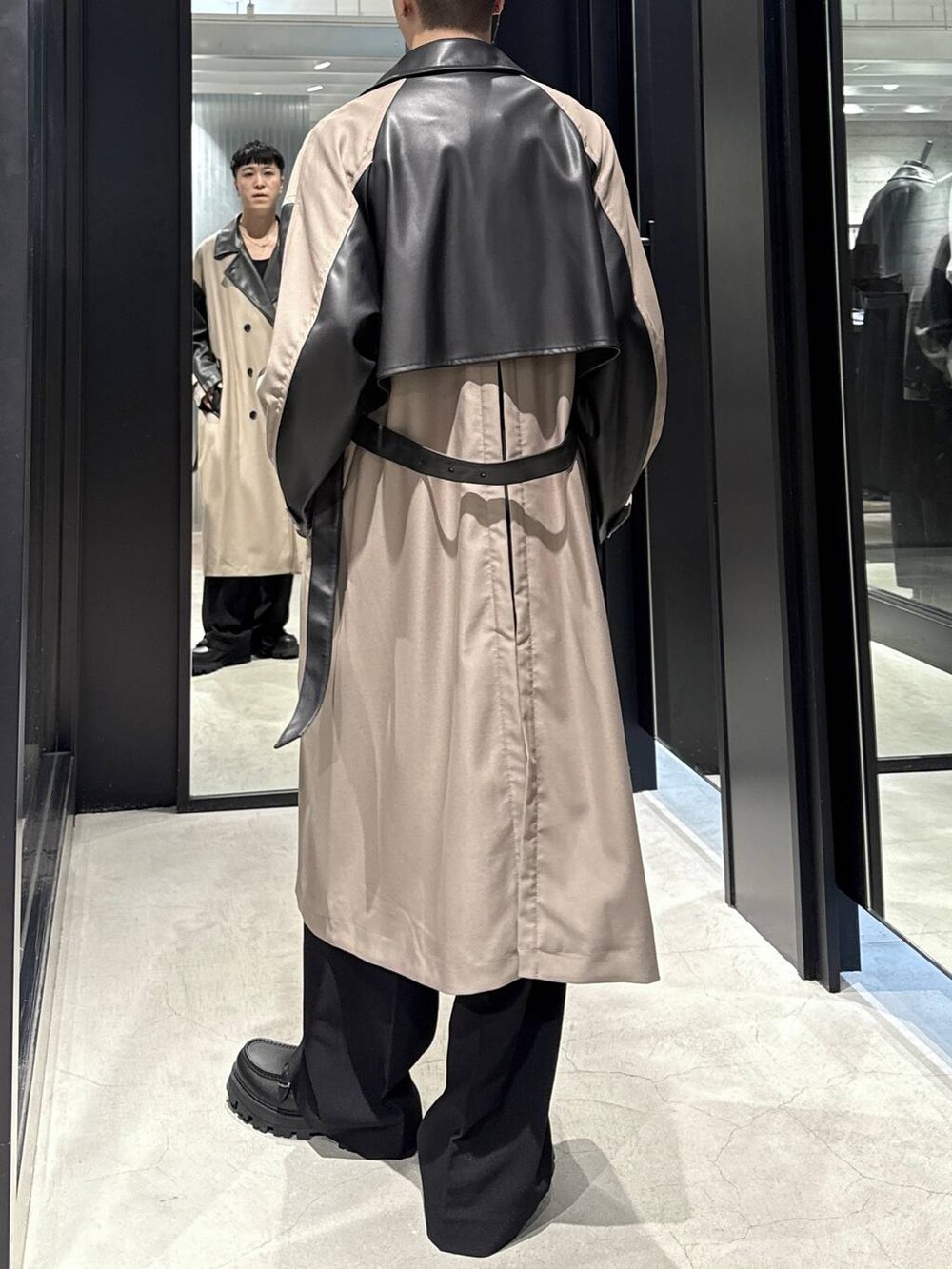 ブラック系のTシャツ/カットソー、ブラック系のドレスシューズ、ベージュ系のトレンチコートを着用したメンズの秋コーディネートの3枚目の写真