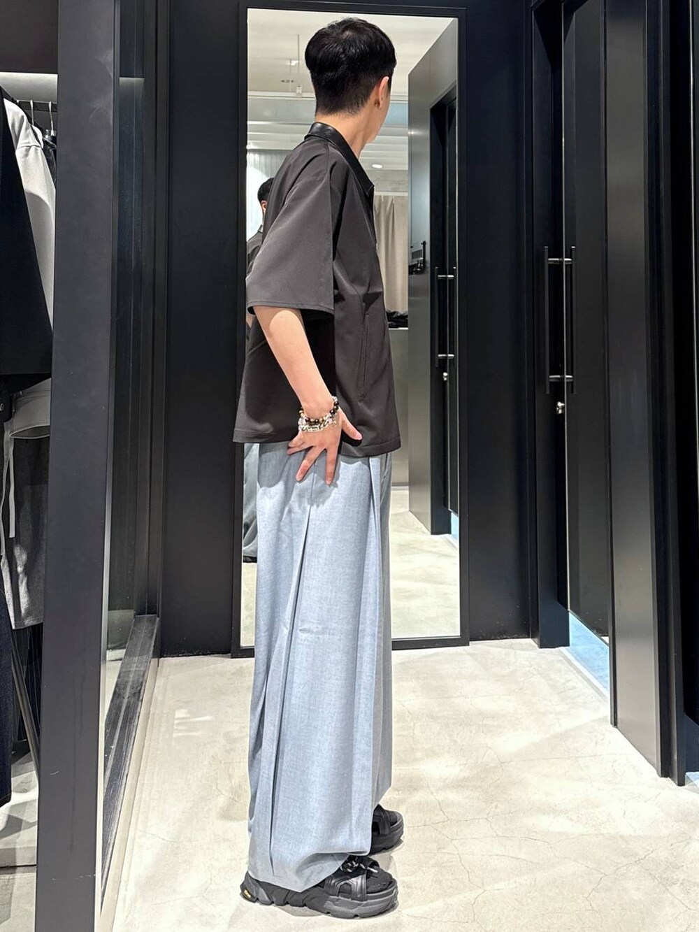 ブラック系のサンダル、ブラック系のタンクトップ、ブルー系のスラックスを着用したメンズの夏コーディネートの2枚目の写真