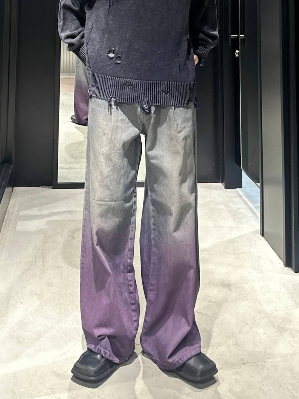 パープル系のデニムパンツ、ブラック系のニット/セーター、シルバー系のネックレスを着用したメンズの秋コーディネートの3枚目の写真