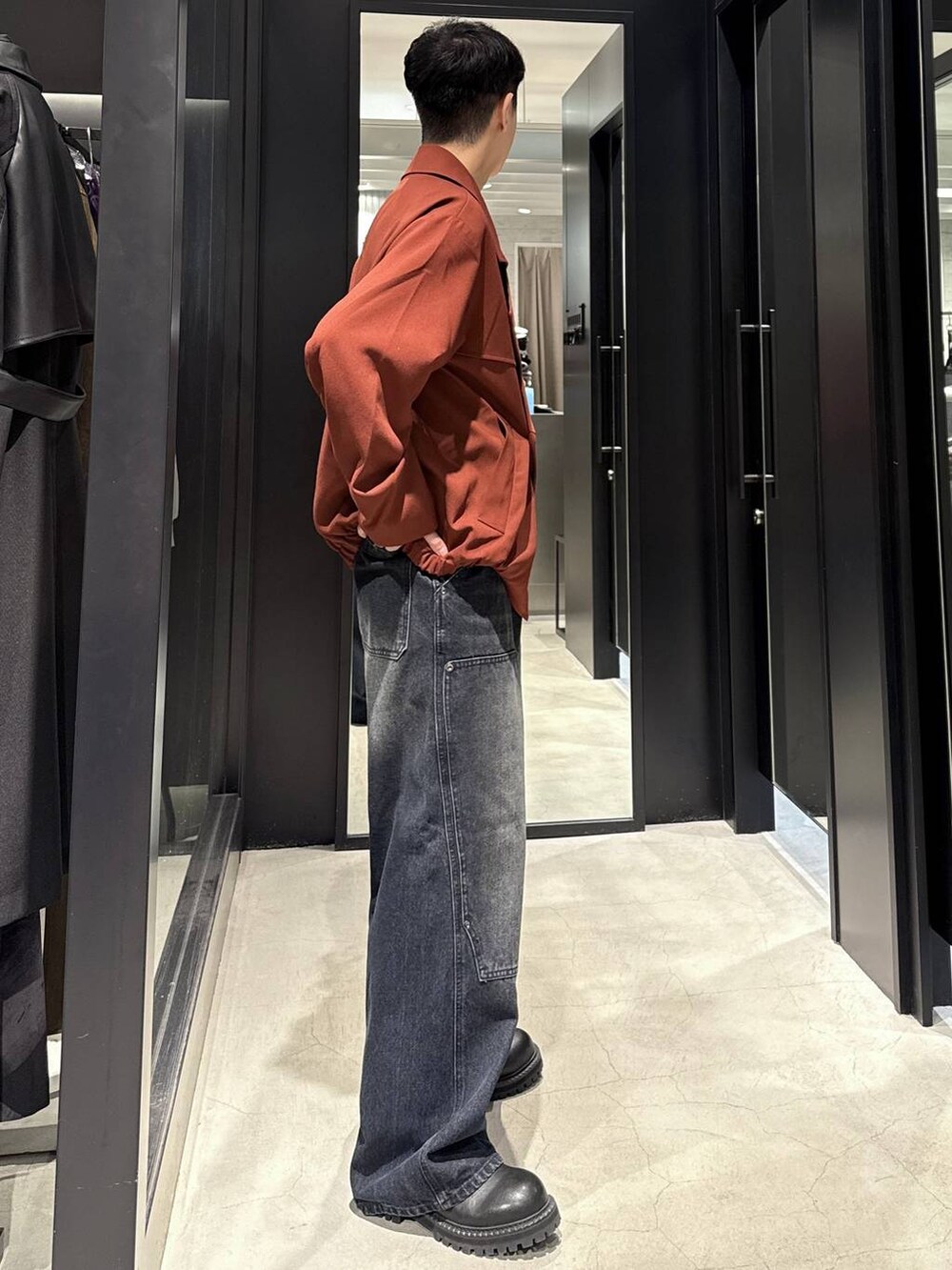 ブラック系のブーツ、ブルー系のデニムパンツ、オレンジ系のブルゾンを着用したメンズの秋コーディネートの2枚目の写真