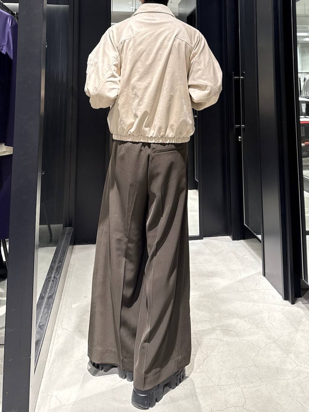 ベージュ系のブルゾン、ブラウン系のスラックス、ホワイト系のネックレスを着用したメンズの冬コーディネートの3枚目の写真