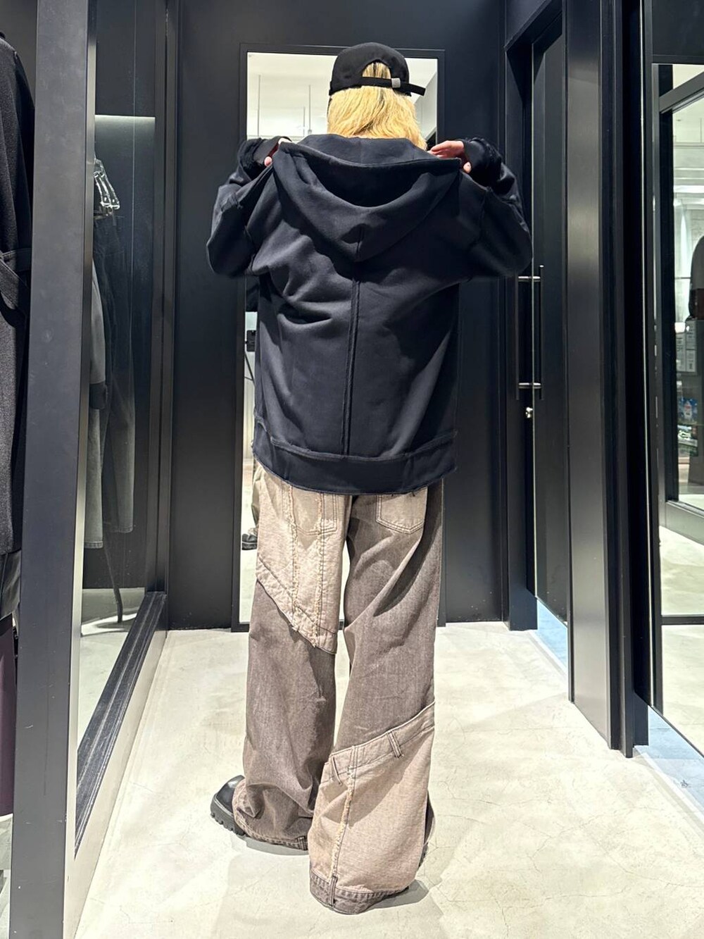 ブラウン系のデニムパンツ、ブラック系のパーカー、ブラック系のキャップを着用したメンズの秋コーディネートの3枚目の写真