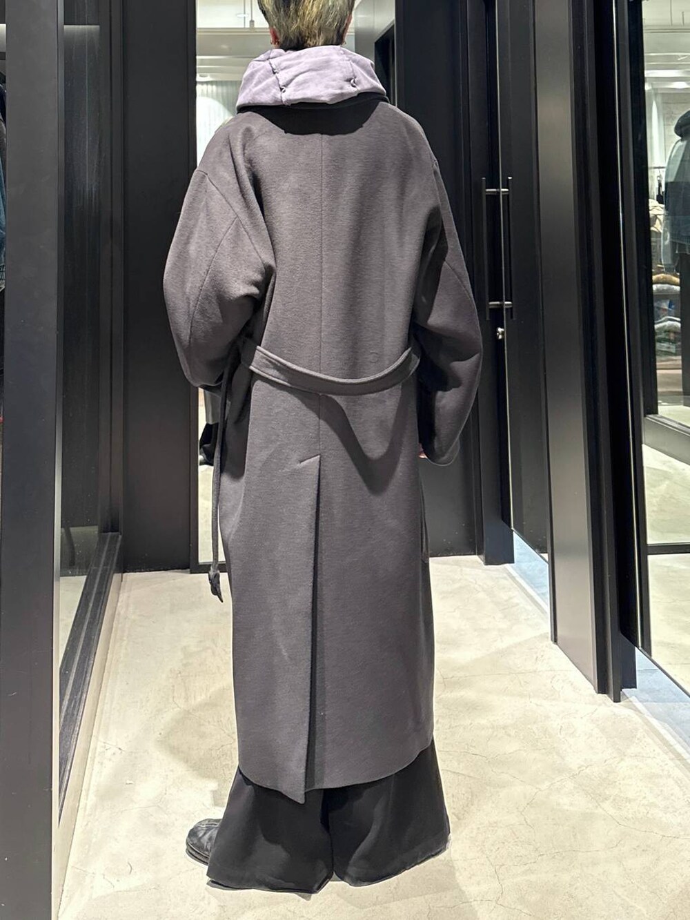 グレー系のトレンチコート、ブラック系のスラックス、パープル系のパーカーを着用したメンズの冬コーディネートの3枚目の写真