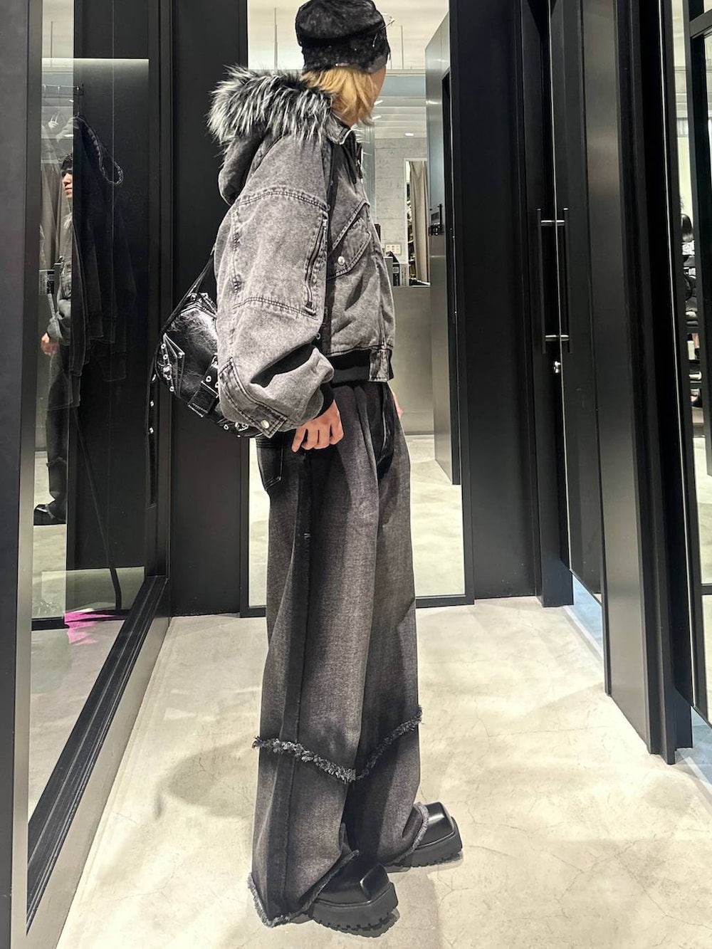 ブラック系のデニムパンツ、ブラック系のショルダーバッグ、グレー系のブルゾンを着用したメンズの秋コーディネートの2枚目の写真