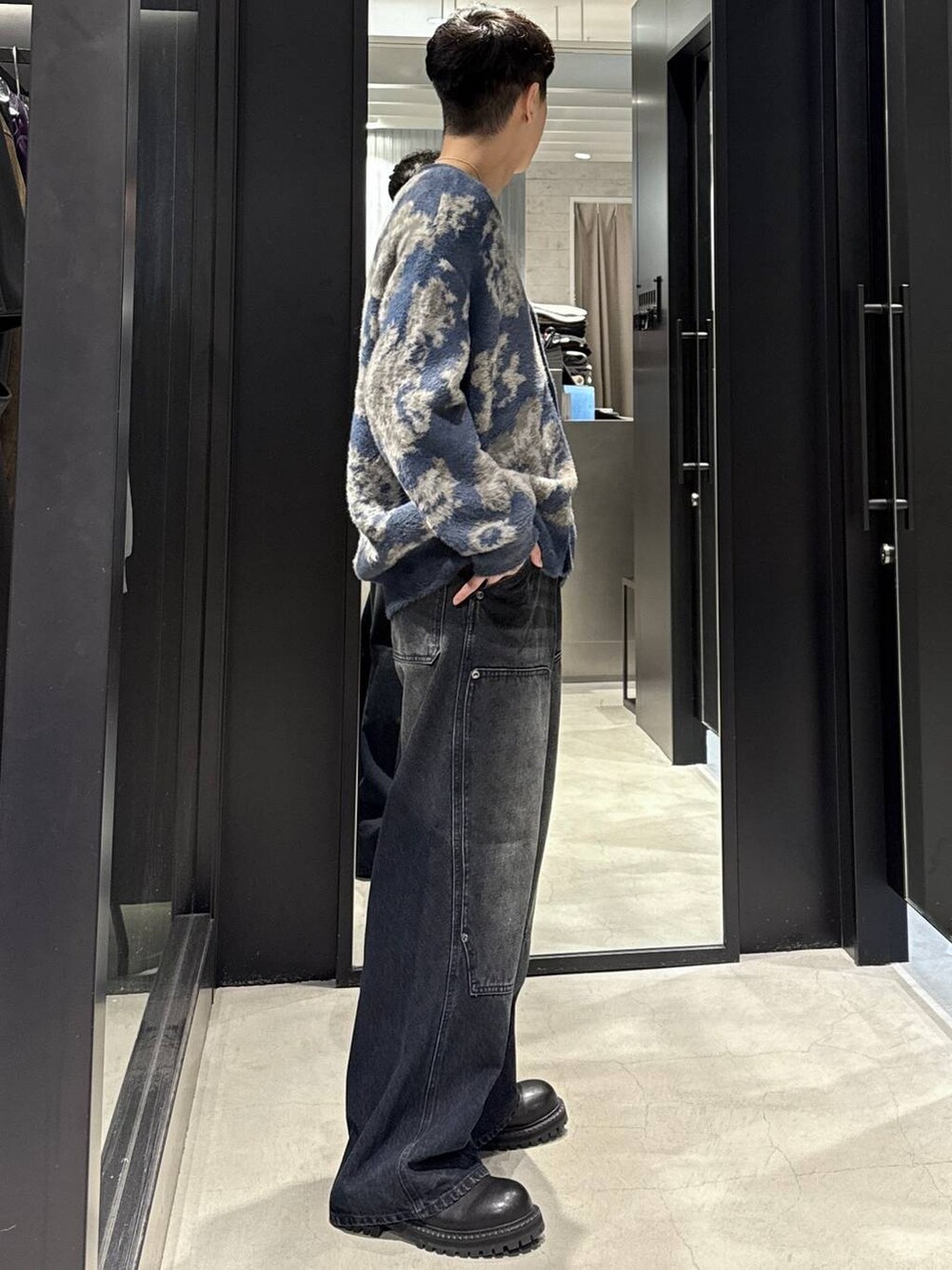 ブルー系のカーディガン/ボレロ、ブラック系のブーツ、ブルー系のデニムパンツを着用したメンズの秋コーディネートの2枚目の写真