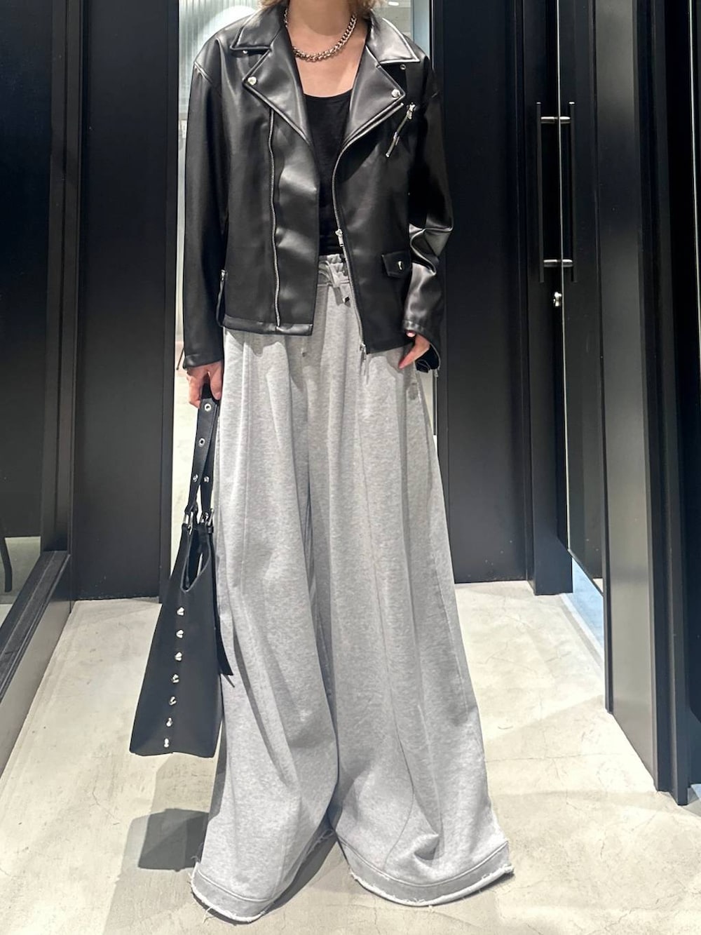 グレー系のスウェットパンツ、ブラック系のライダースジャケット、ブラック系のトートバッグを着用したメンズの秋コーディネートの2枚目の写真