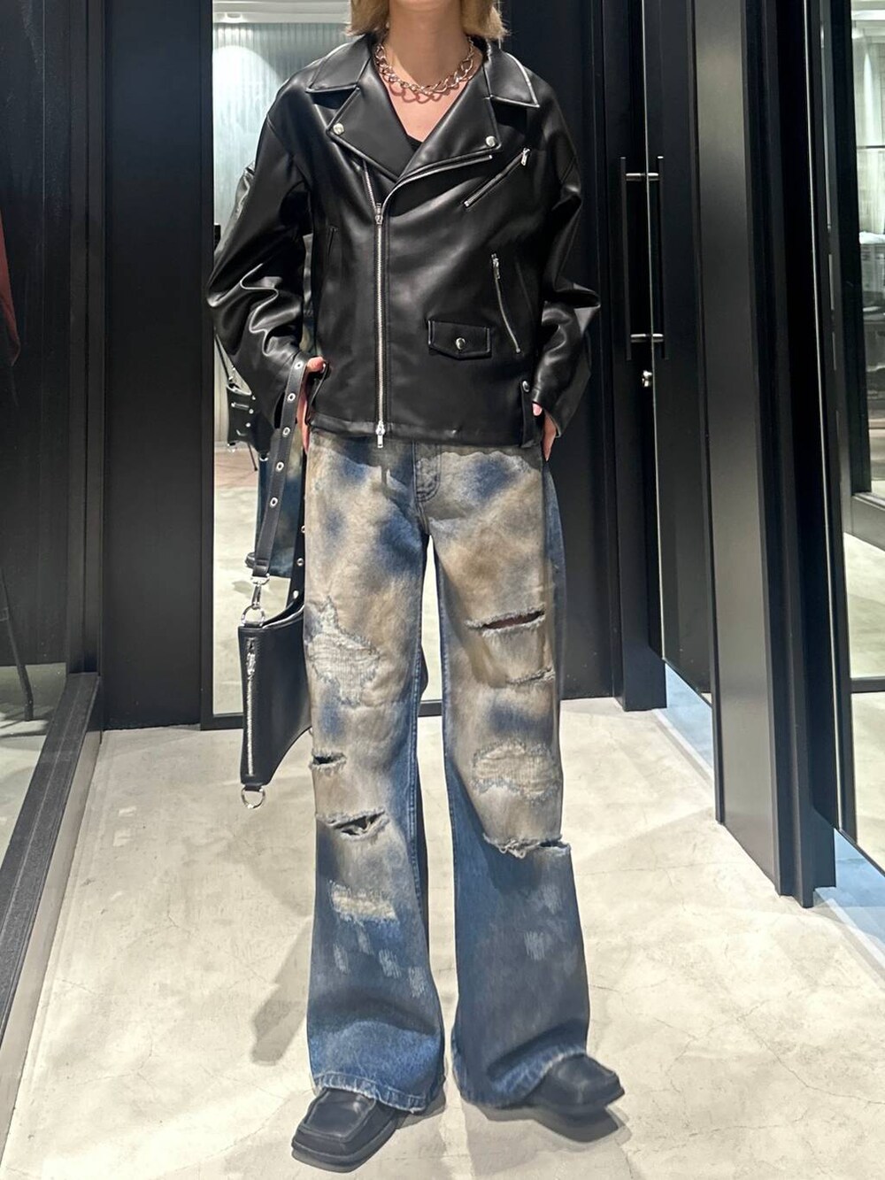 ブラック系のショルダーバッグ、ブラック系のライダースジャケット、ブルー系のデニムパンツを着用したメンズの秋コーディネートの4枚目の写真