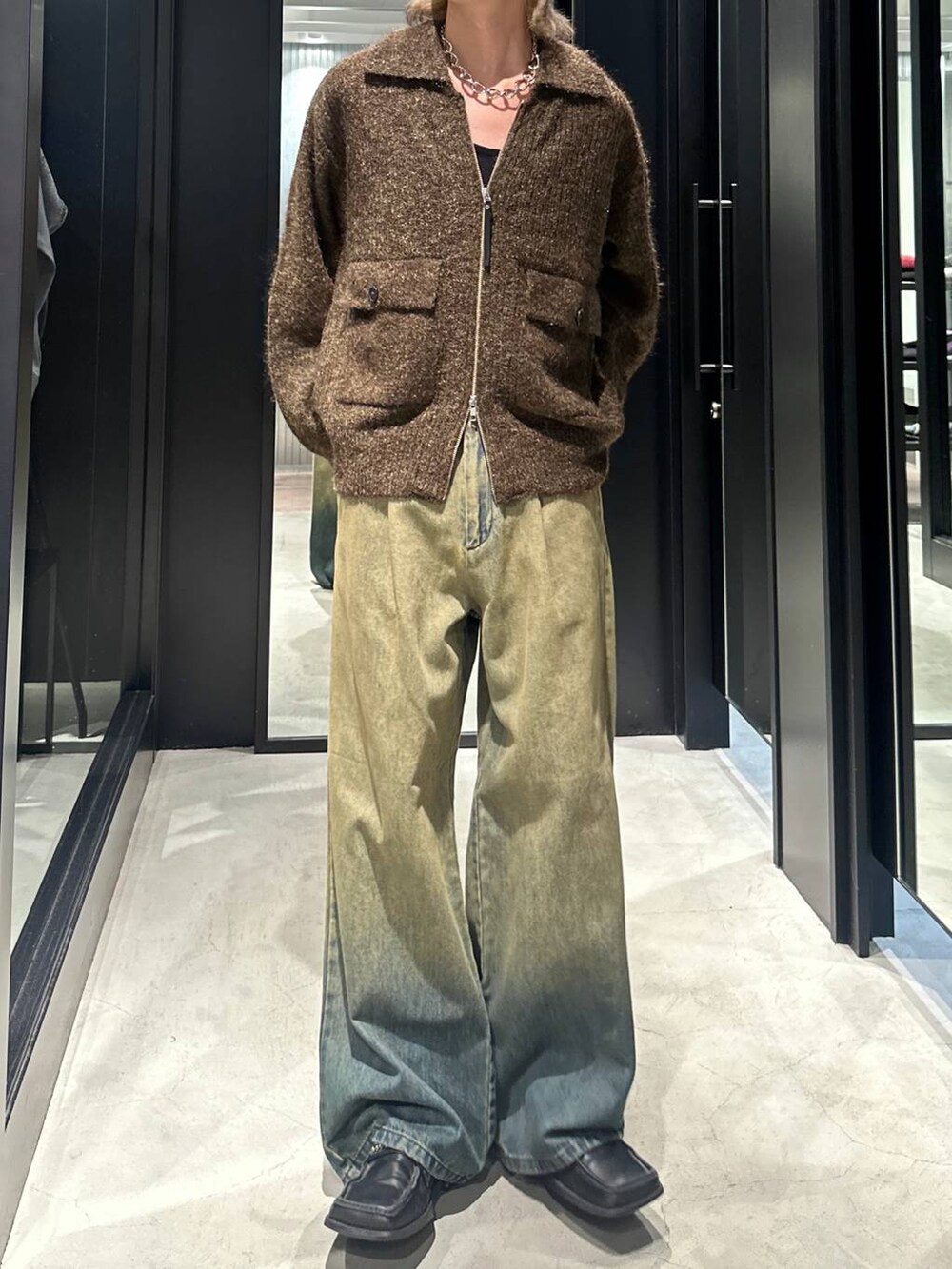 グリーン系のデニムパンツ、イエロー系のニット/セーター、シルバー系のネックレスを着用したメンズの秋コーディネートの5枚目の写真