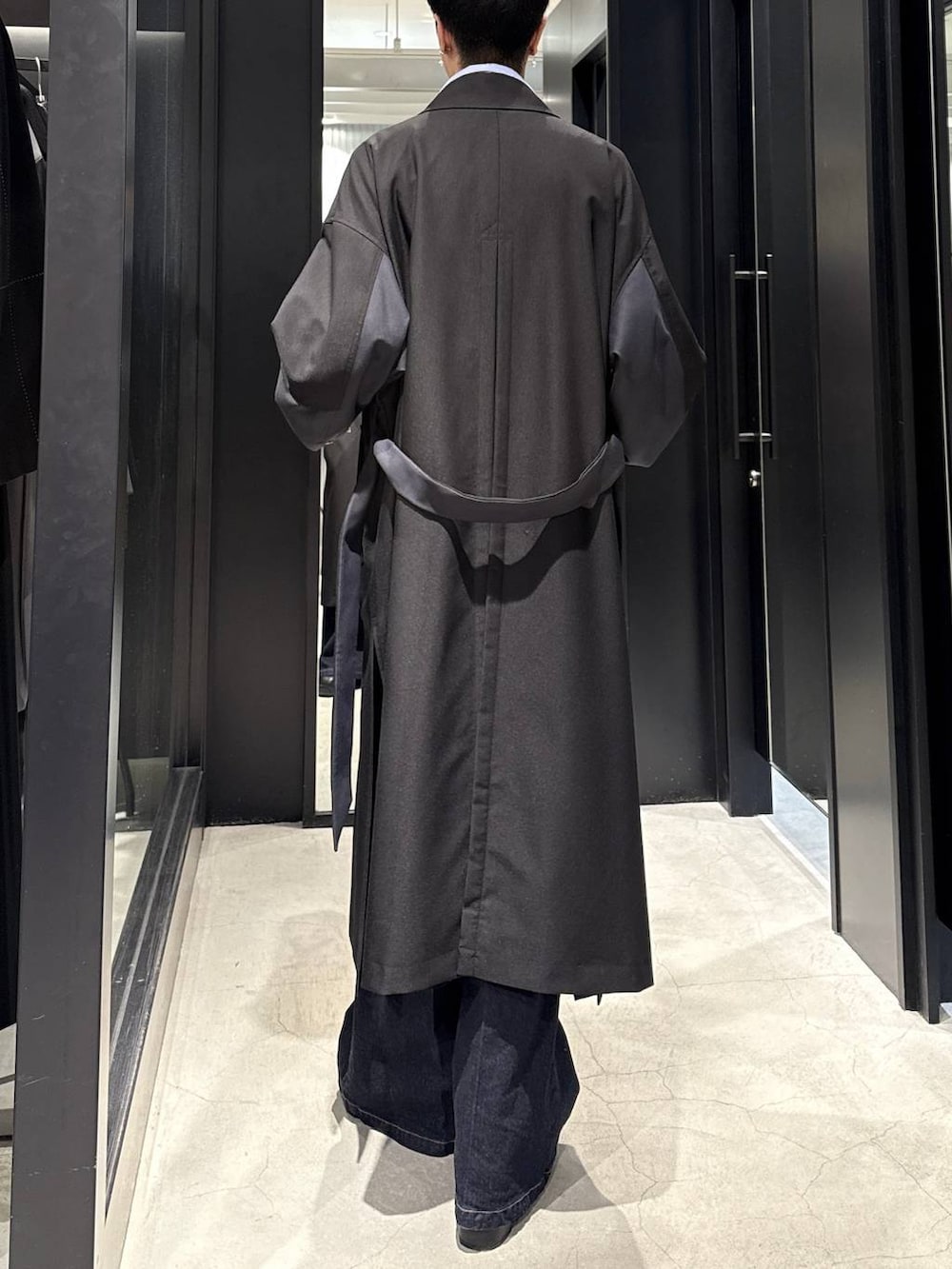 ブラック系のブーツ、ブルー系のデニムパンツ、ブラック系のトレンチコートを着用したメンズの冬コーディネートの3枚目の写真