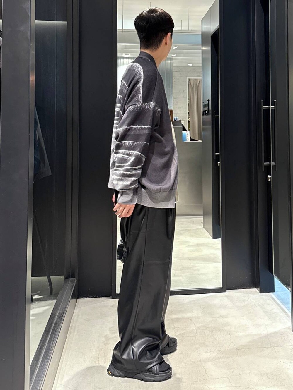 ブラック系のサンダル、ブラック系のスラックス、ブラック系のカーディガン/ボレロを着用したメンズの夏コーディネートの2枚目の写真