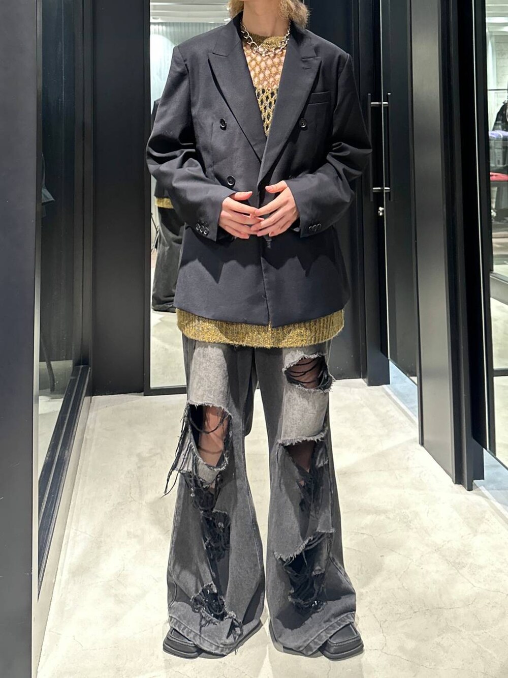 ブラック系のデニムパンツ、ブラック系のテーラードジャケット、イエロー系のニット/セーターを着用したメンズの秋コーディネートの2枚目の写真