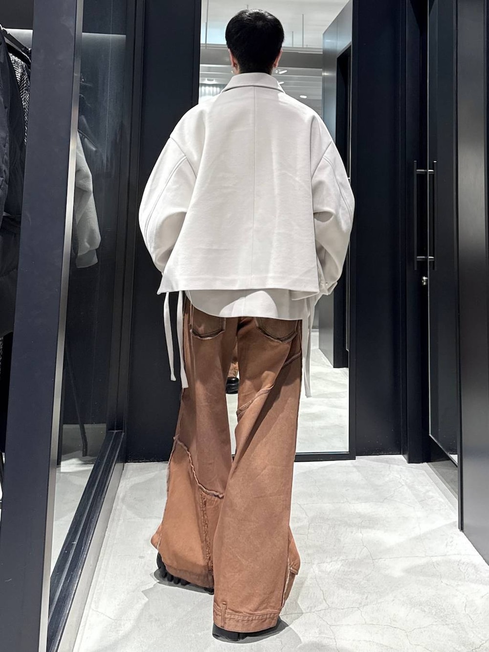 ホワイト系のブルゾン、オレンジ系のデニムパンツ、シルバー系のネックレスを着用したメンズの冬コーディネートの3枚目の写真