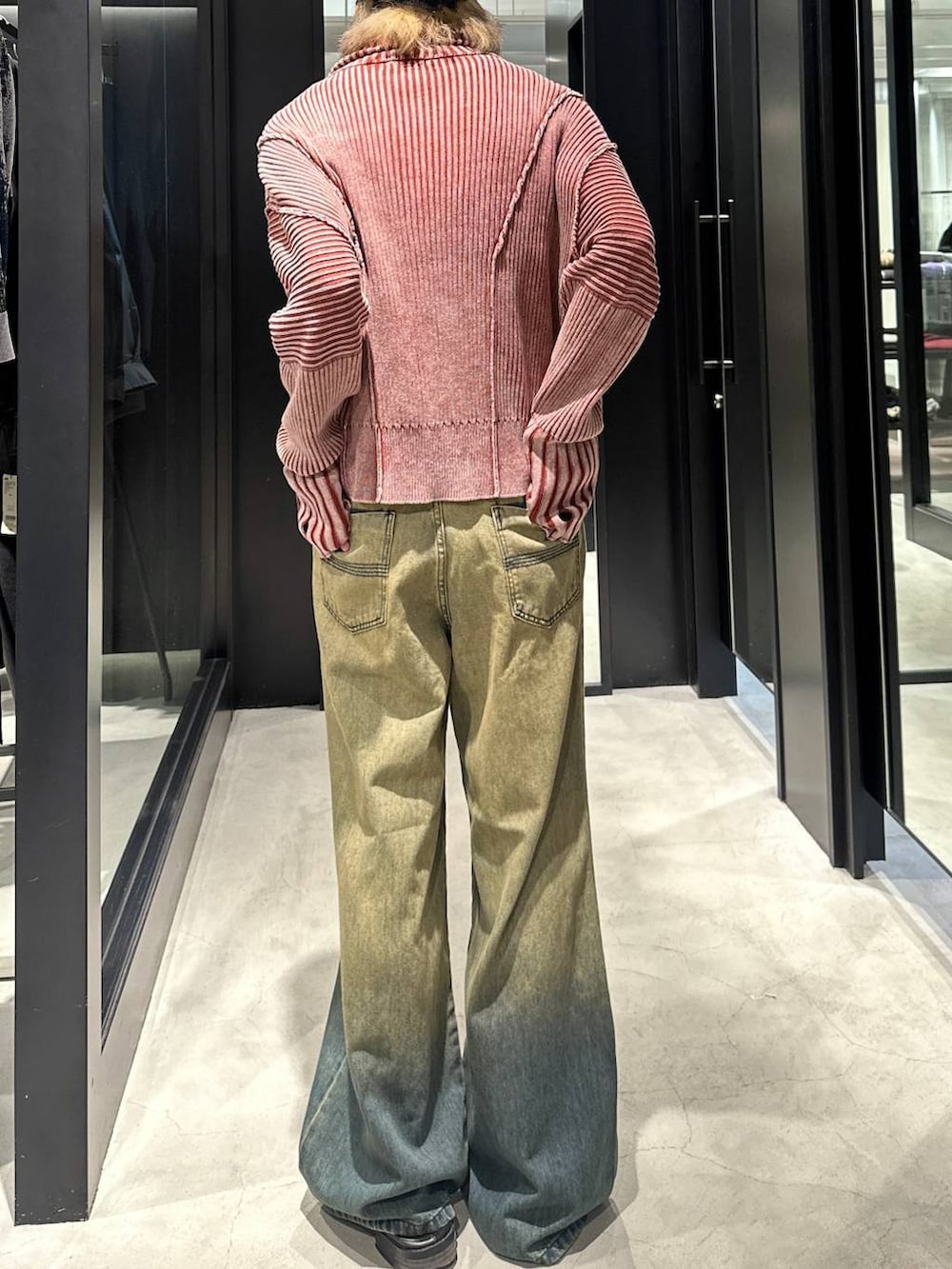 グリーン系のデニムパンツ、オレンジ系のニット/セーター、シルバー系のネックレスを着用したメンズの秋コーディネートの3枚目の写真