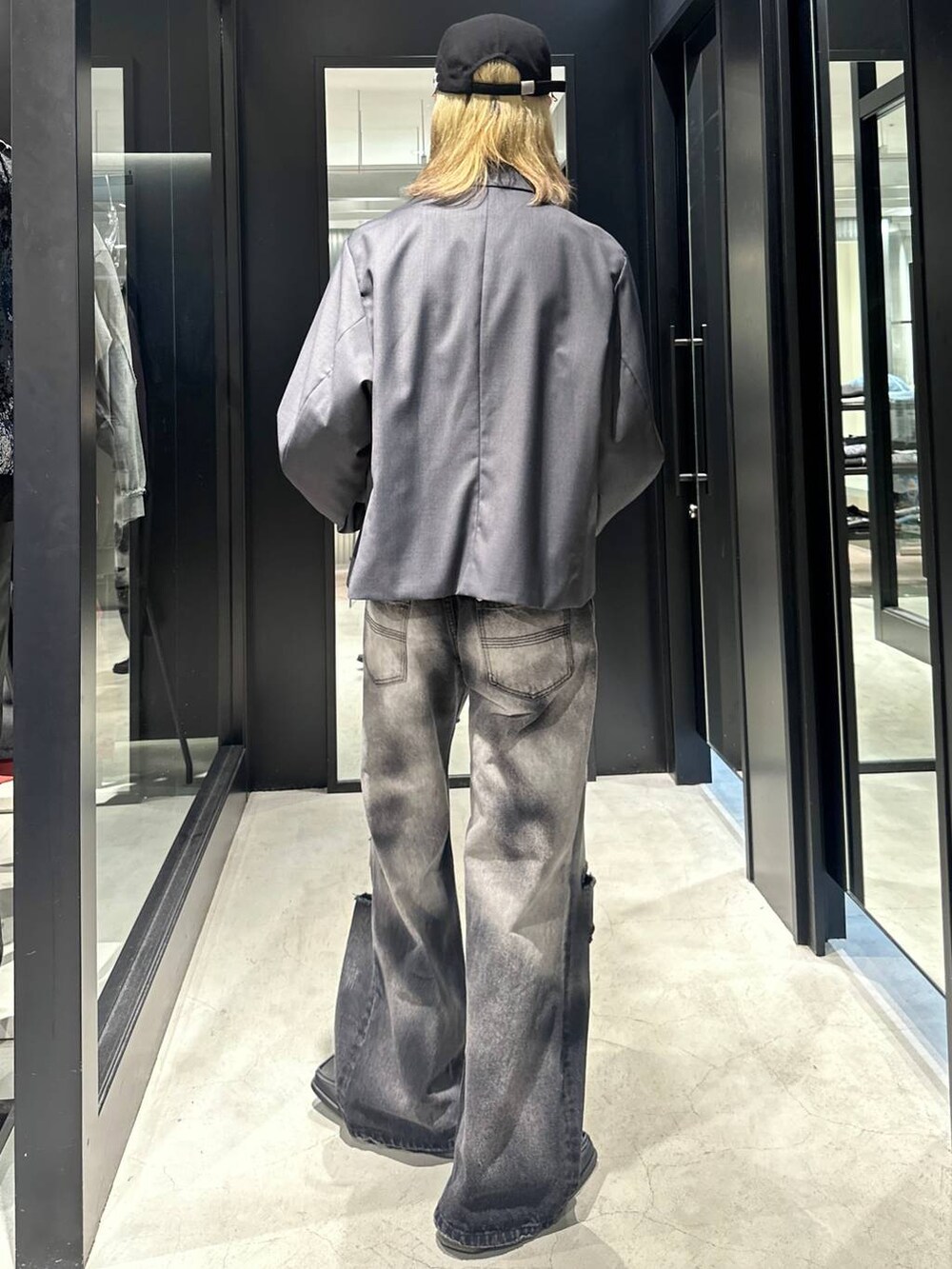 グレー系のテーラードジャケット、ブラック系のデニムパンツ、ブラック系のキャップを着用したメンズの秋コーディネートの3枚目の写真