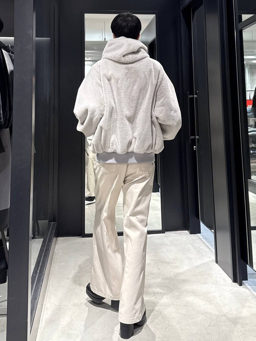 グレー系のブルゾン、ブラック系のブーツ、ホワイト系のデニムパンツを着用したメンズの冬コーディネートの3枚目の写真