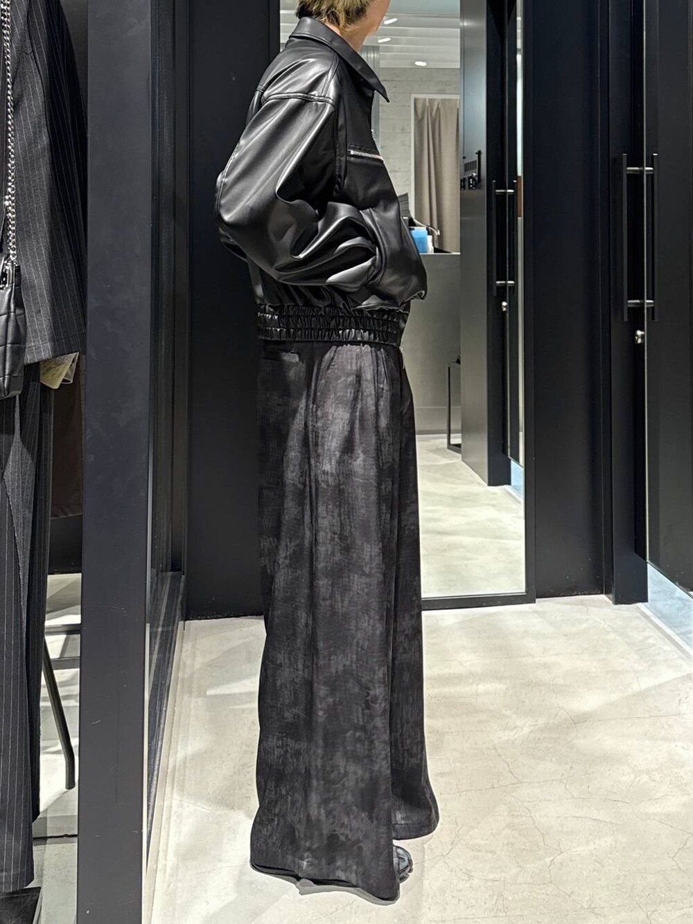 グレー系のスラックス、ブラック系のキャップ、シルバー系のネックレスを着用したメンズの冬コーディネートの2枚目の写真