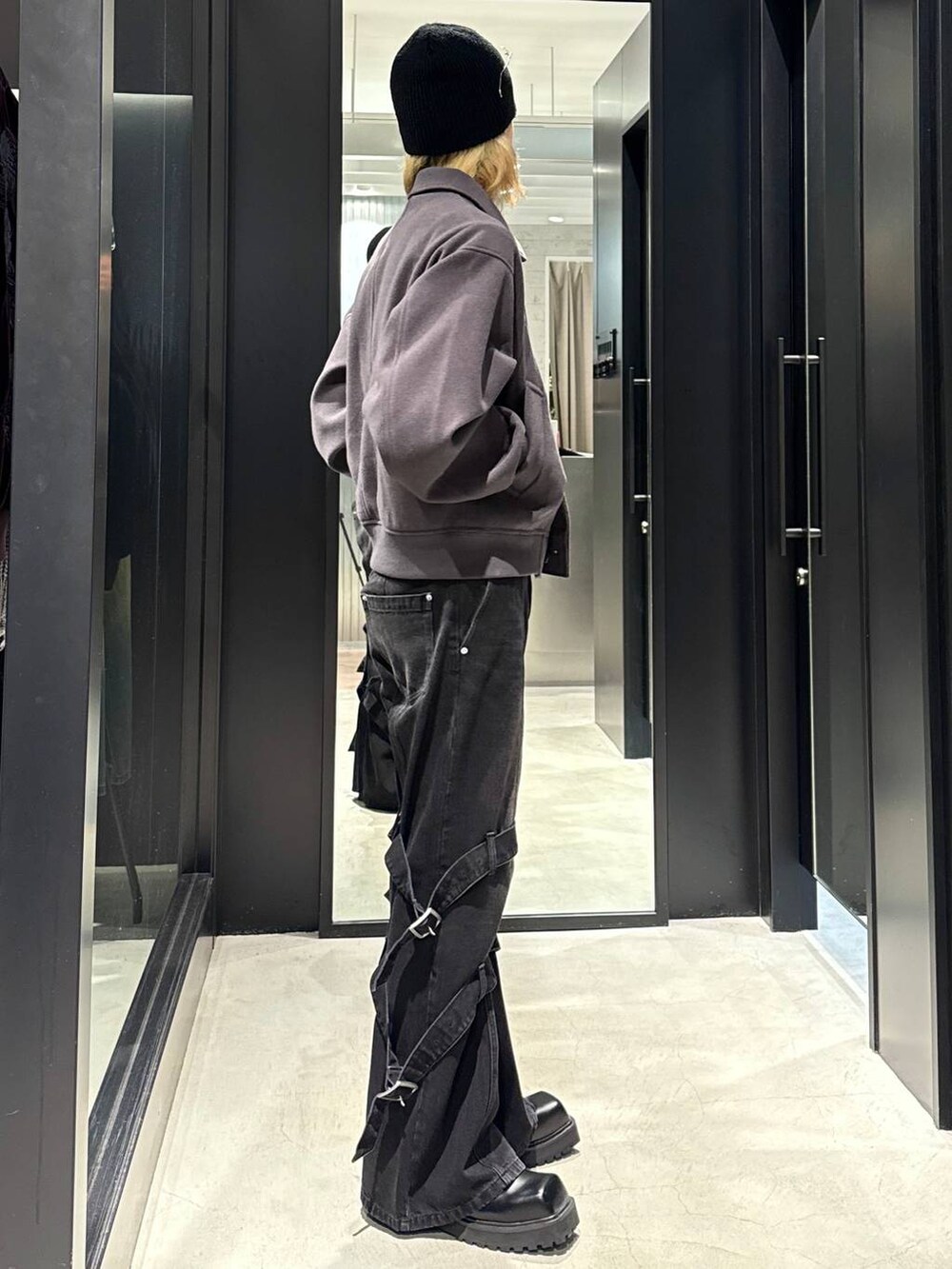 グレー系のブルゾン、ブラック系のドレスシューズ、ブラック系のデニムパンツを着用したメンズの秋コーディネートの2枚目の写真