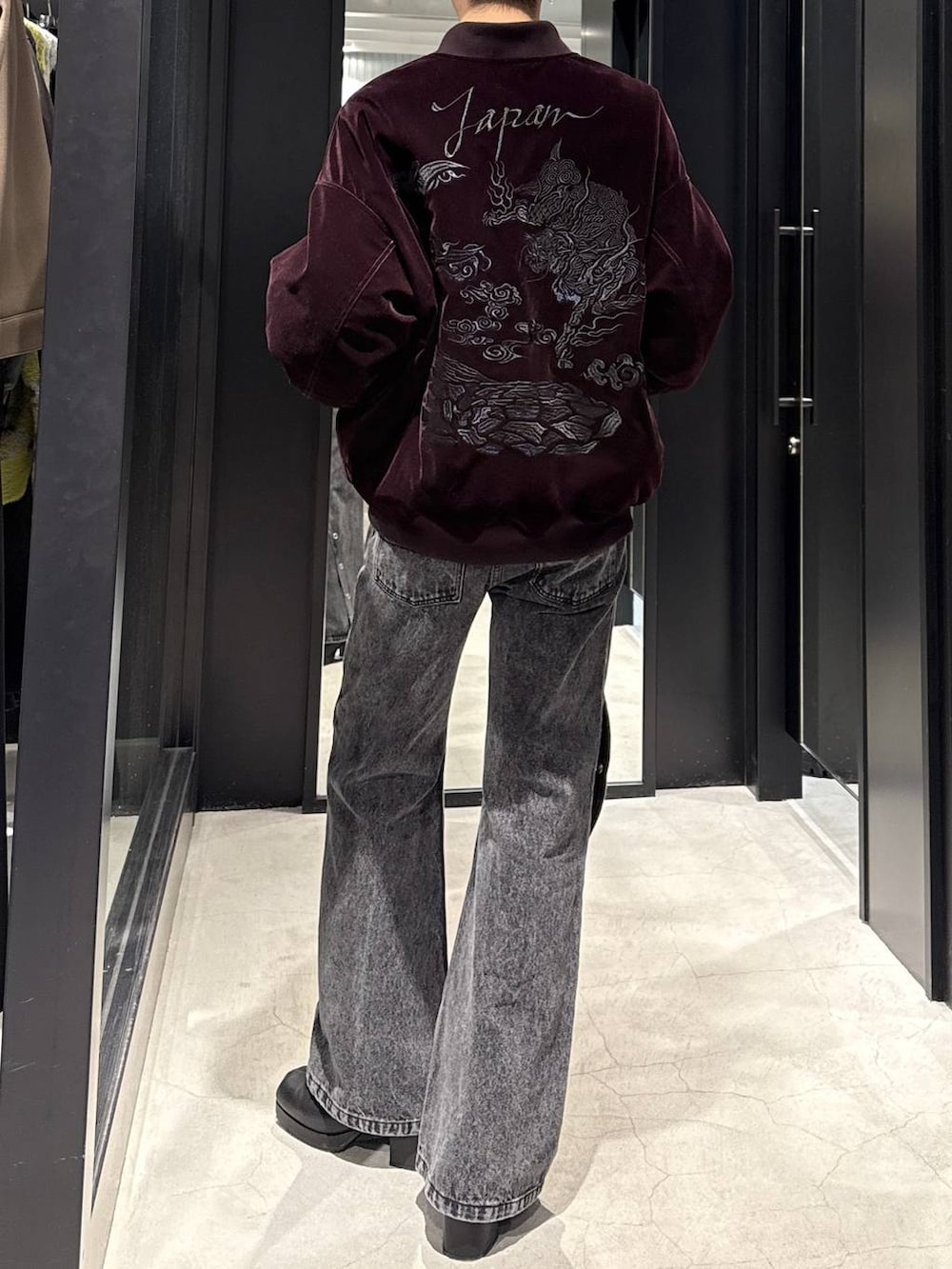 ブラック系のブーツ、ブラック系のデニムパンツ、ホワイト系のネックレスを着用したメンズの冬コーディネートの2枚目の写真