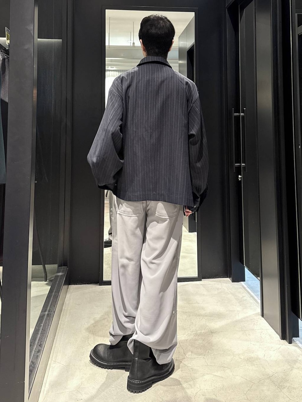 ブルー系のブルゾン、ブラック系のブーツ、シルバー系のネックレスを着用したメンズの秋コーディネートの3枚目の写真