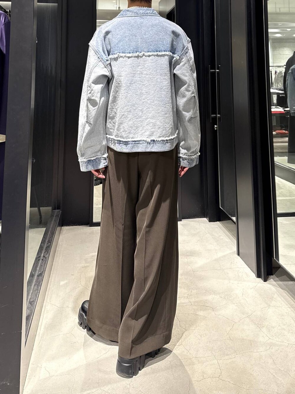 ブルー系のブルゾン、ブラウン系のスラックス、ホワイト系のネックレスを着用したメンズの冬コーディネートの3枚目の写真