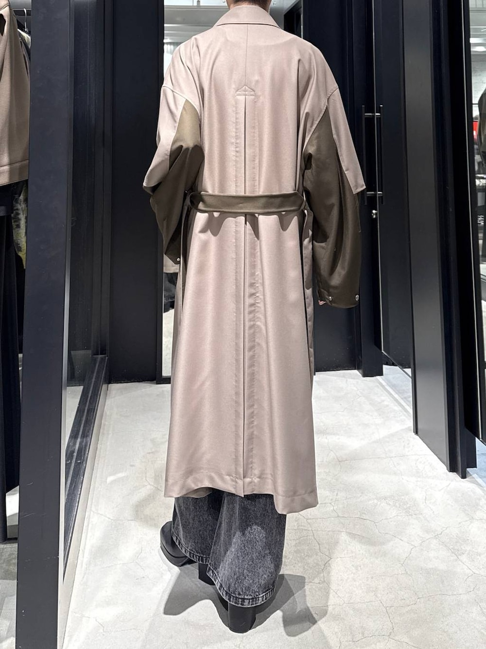 ブラック系のブーツ、ベージュ系のトレンチコート、ブラック系のデニムパンツを着用したメンズの冬コーディネートの2枚目の写真