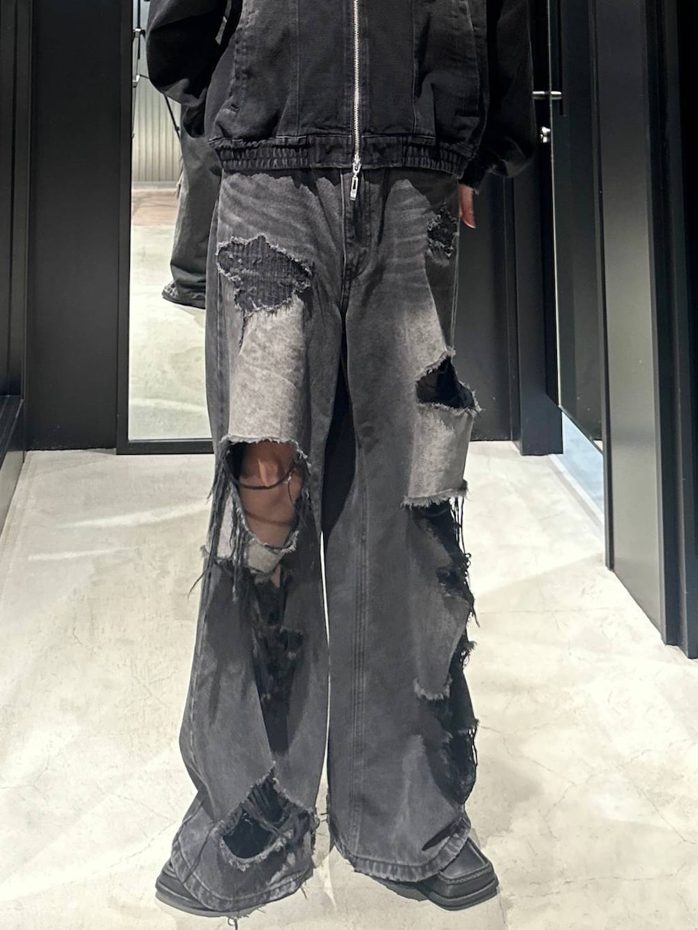 ブラック系のデニムパンツ、ブラック系のブルゾン、シルバー系のネックレスを着用したメンズの秋コーディネートの3枚目の写真