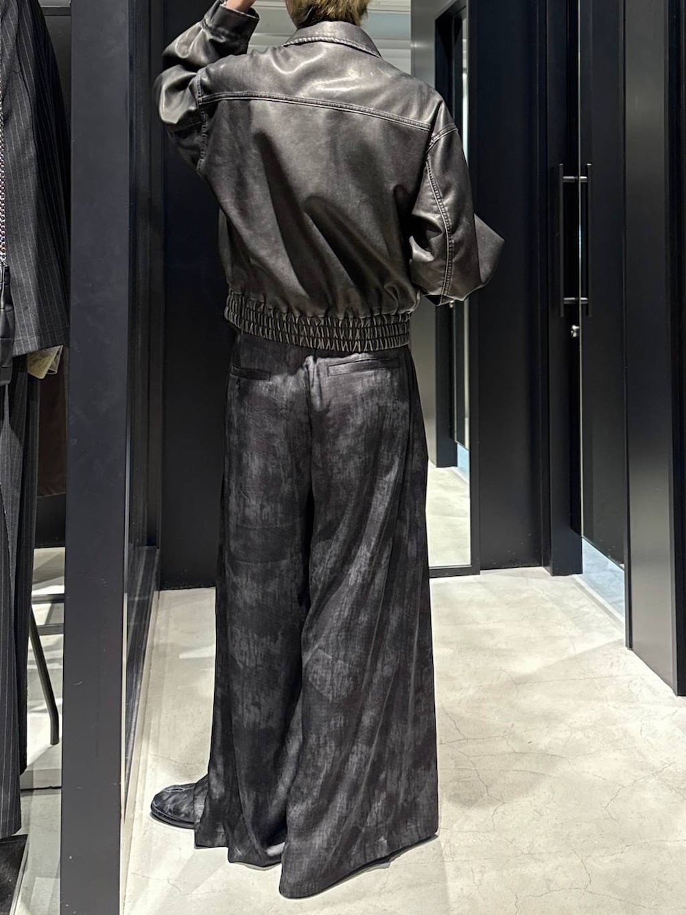 グレー系のスラックス、ブラック系のキャップ、シルバー系のネックレスを着用したメンズの冬コーディネートの3枚目の写真