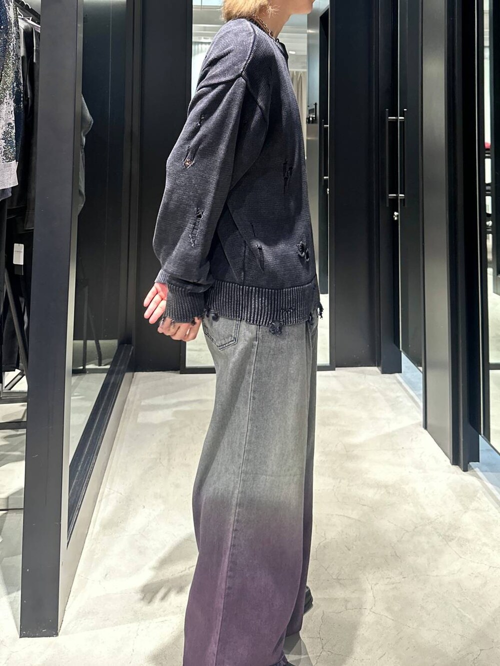パープル系のデニムパンツ、ブラック系のニット/セーター、シルバー系のネックレスを着用したメンズの秋コーディネートの4枚目の写真