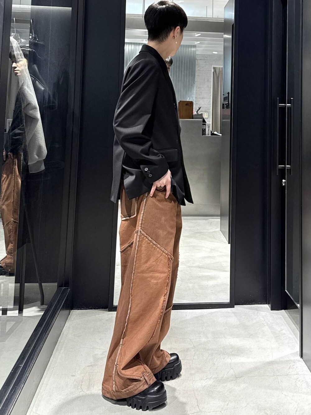 オレンジ系のデニムパンツ、ブラック系のテーラードジャケット、シルバー系のネックレスを着用したメンズの冬コーディネートの2枚目の写真