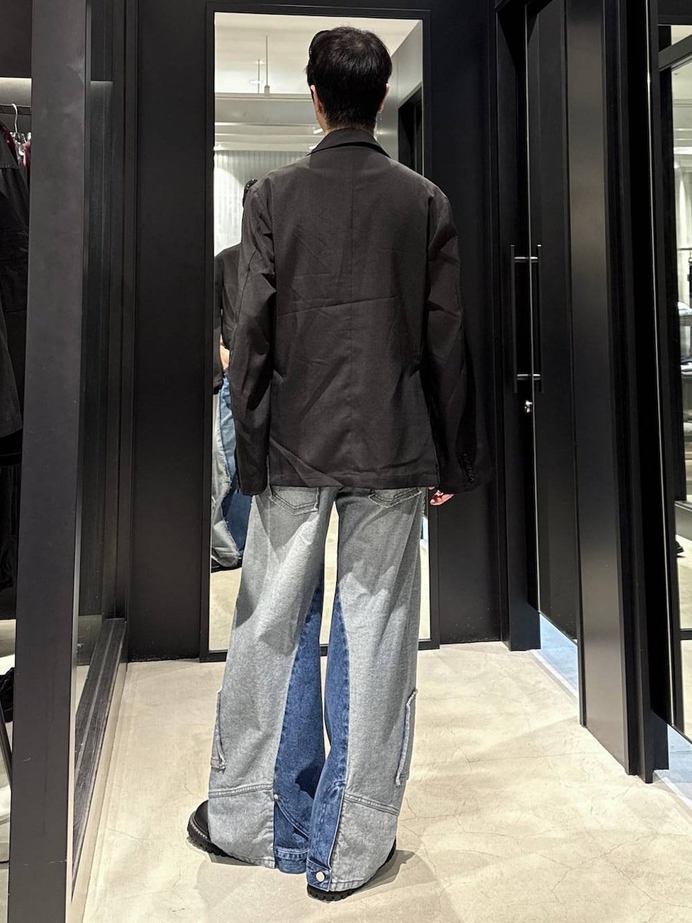 ブラック系のタンクトップ、ブルー系のデニムパンツ、ブラック系のテーラードジャケットを着用したメンズの秋コーディネートの3枚目の写真