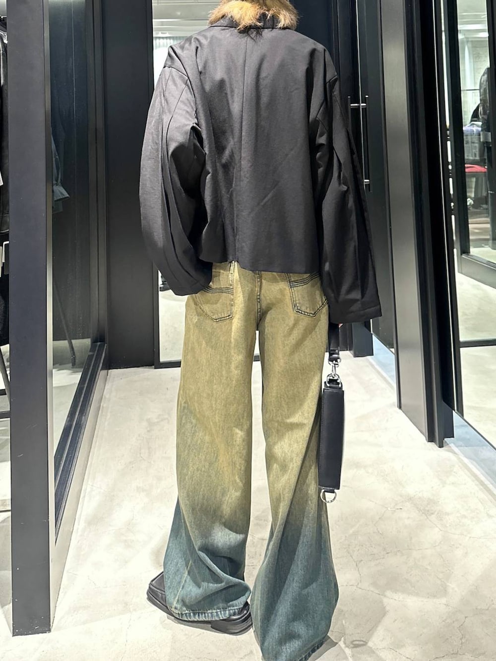 グリーン系のデニムパンツ、ブラック系のショルダーバッグ、ブラック系のテーラードジャケットを着用したメンズの秋コーディネートの3枚目の写真
