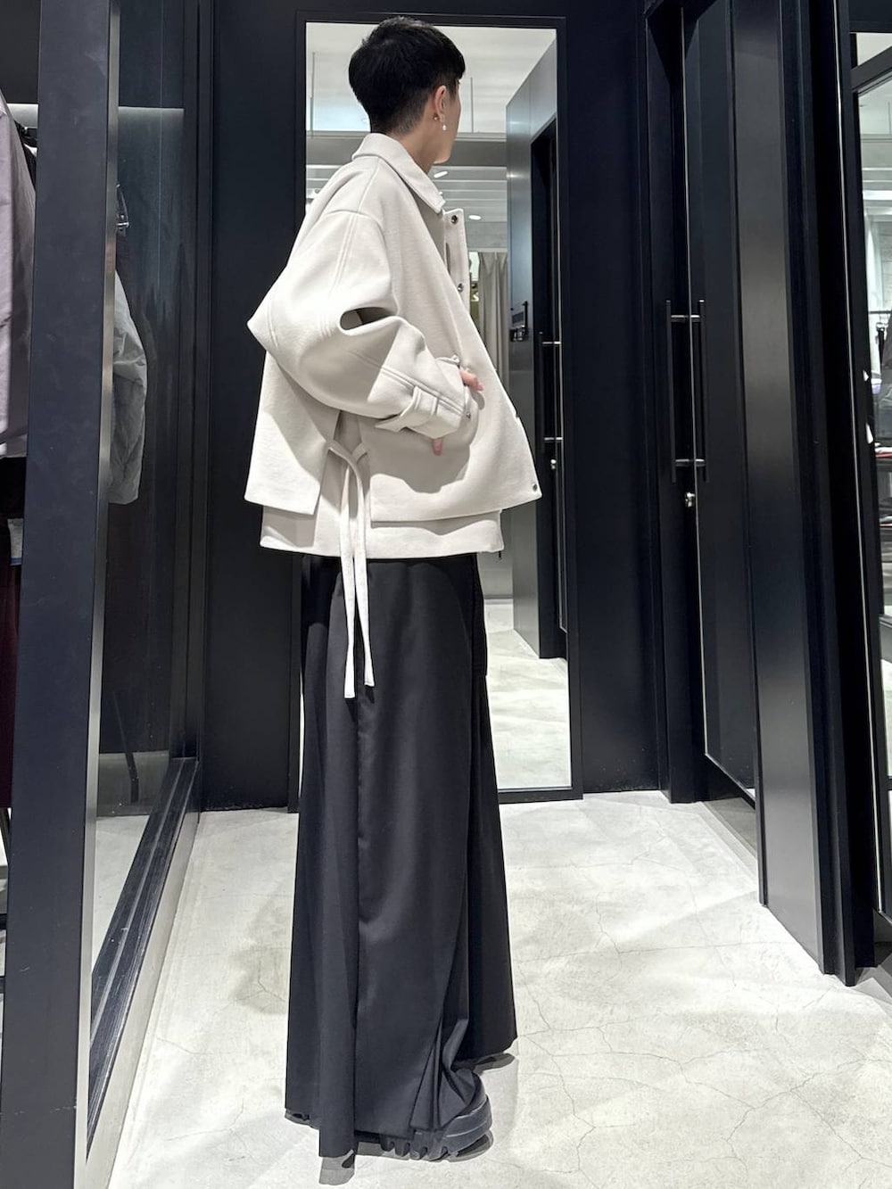 ホワイト系のブルゾン、ブラック系のスラックスを着用したメンズの冬コーディネートの2枚目の写真