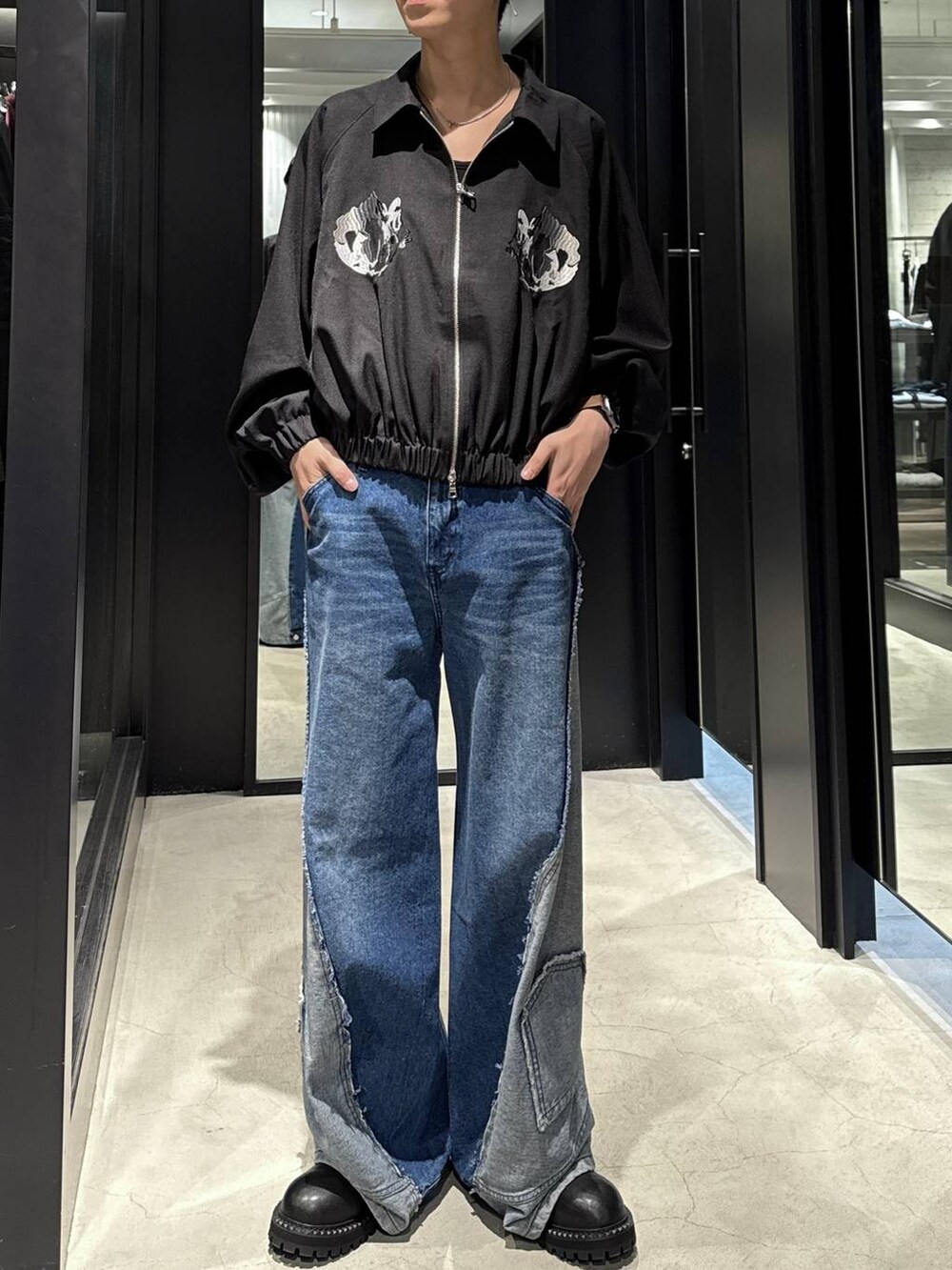 ホワイト系のTシャツ/カットソー、ブルー系のデニムパンツ、ブラック系のブーツを着用したメンズの秋コーディネートの4枚目の写真