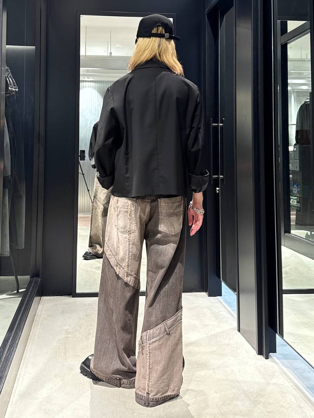 ブラウン系のデニムパンツ、ブラック系のテーラードジャケット、ブラック系のキャップを着用したメンズの秋コーディネートの4枚目の写真