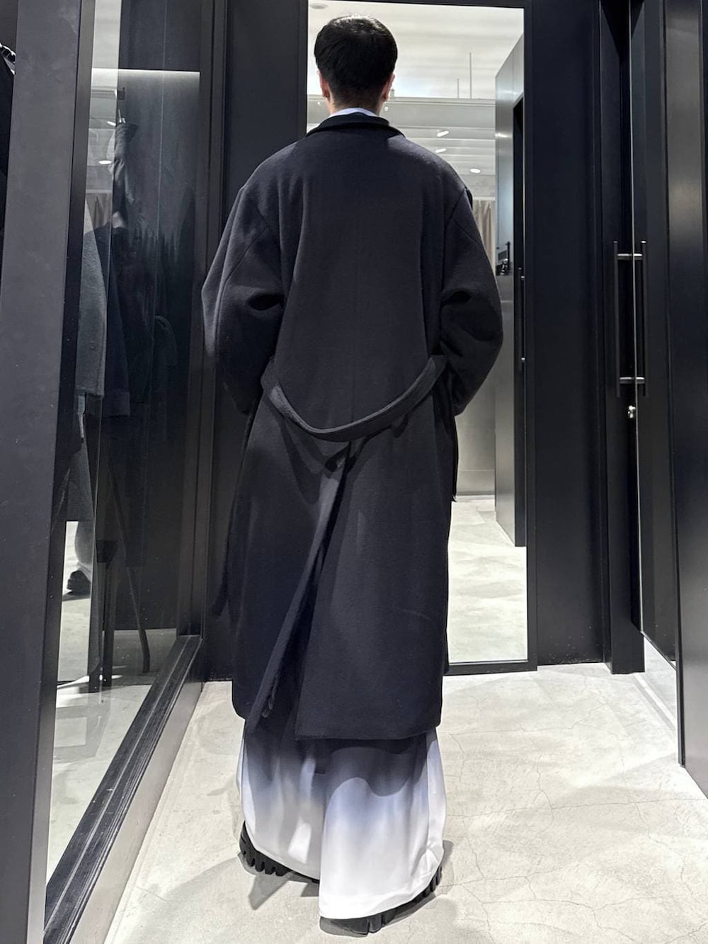 ブラック系のチェスターコート、ブラック系のカーディガン/ボレロ、ブルー系のシャツ/ブラウスを着用したメンズの冬コーディネートの3枚目の写真