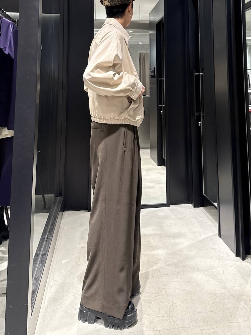 ベージュ系のブルゾン、ブラウン系のスラックス、ホワイト系のネックレスを着用したメンズの冬コーディネートの2枚目の写真