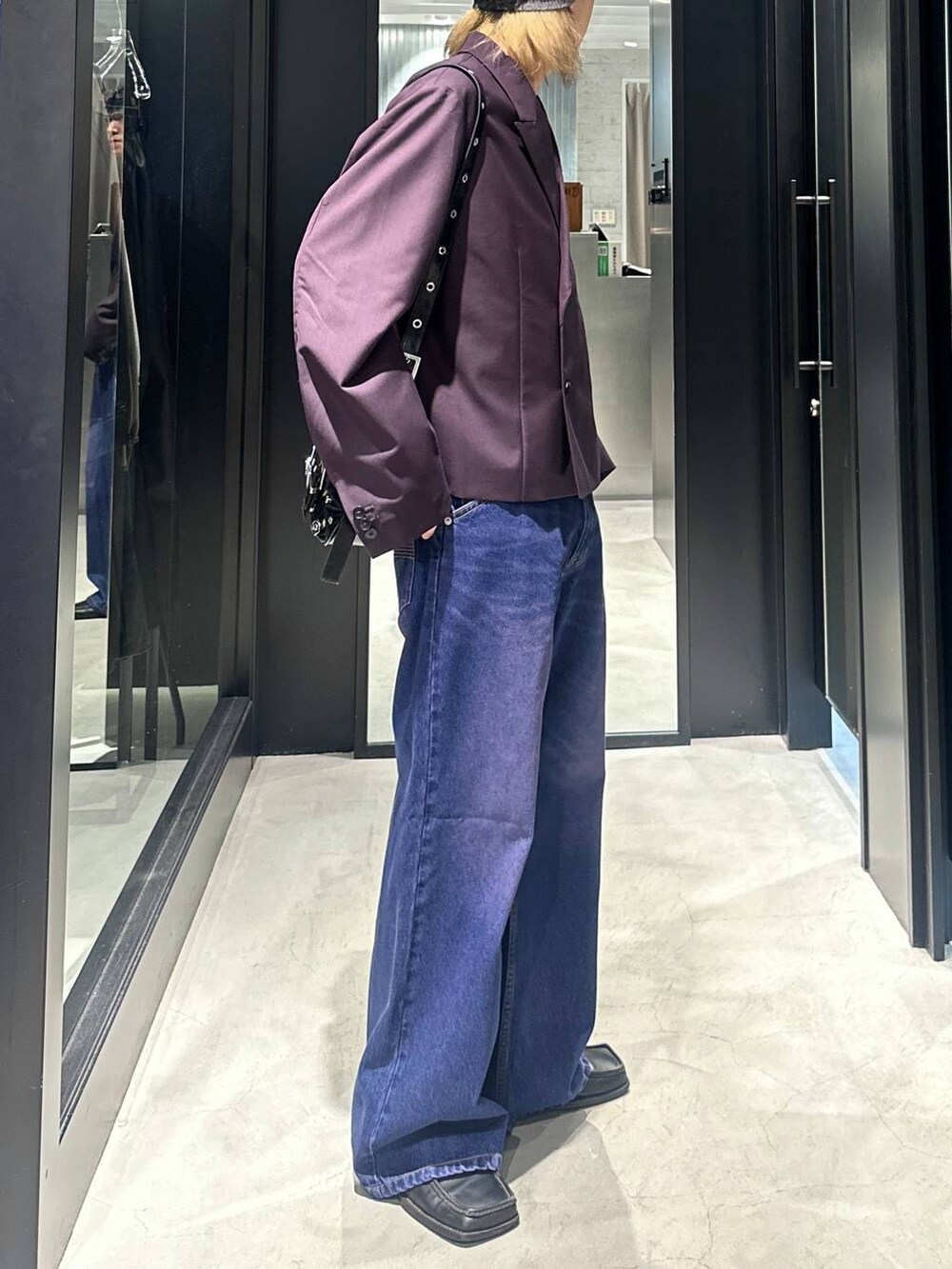 パープル系のデニムパンツ、レッド系のテーラードジャケット、ブラック系のショルダーバッグを着用したメンズの秋コーディネートの2枚目の写真