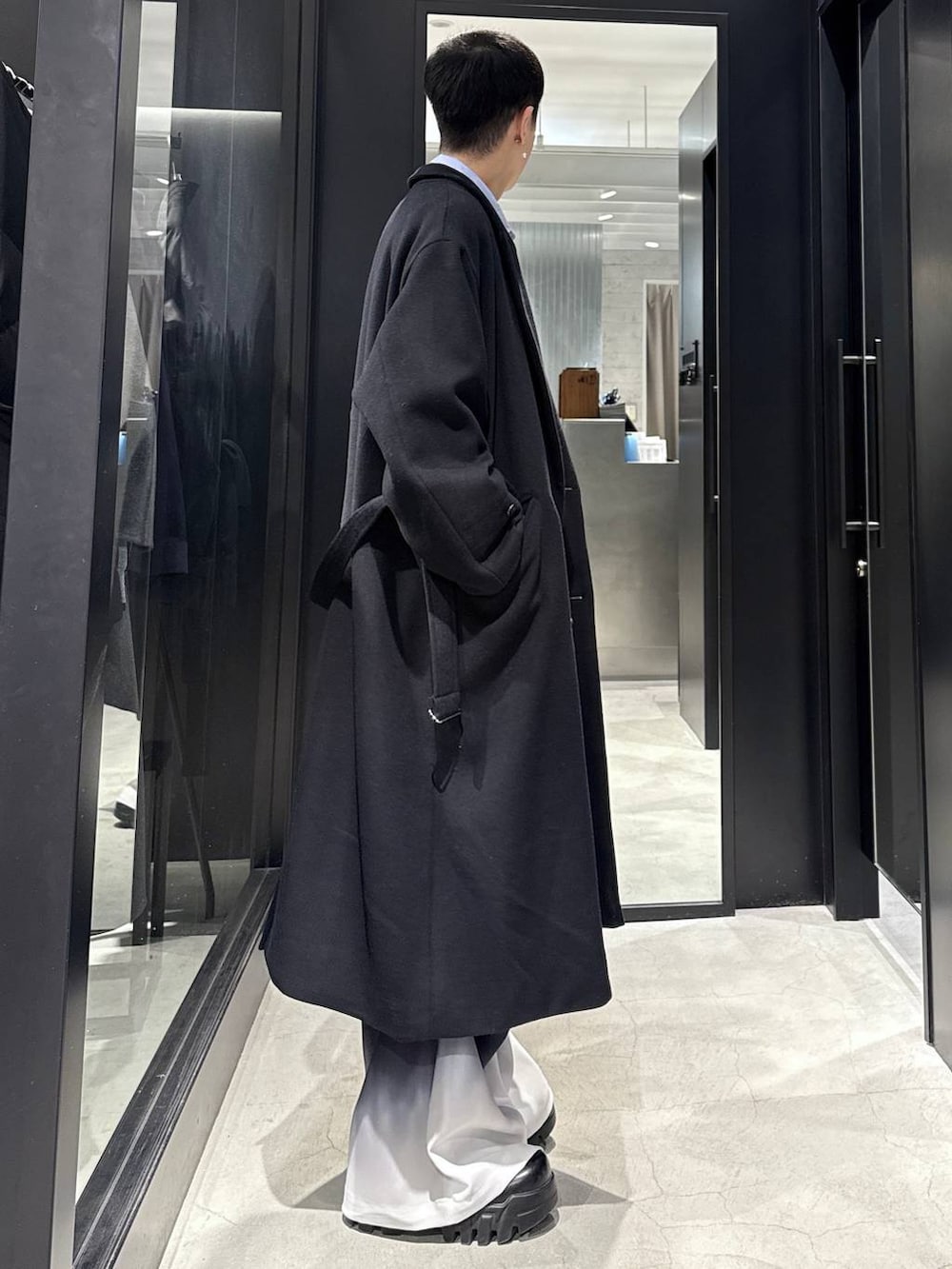 ブラック系のチェスターコート、ブラック系のカーディガン/ボレロ、ブルー系のシャツ/ブラウスを着用したメンズの冬コーディネートの2枚目の写真