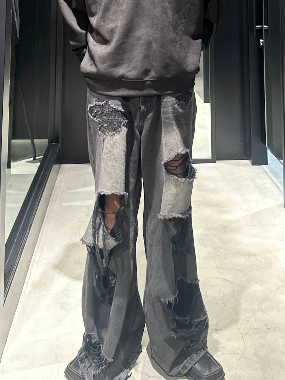 ブラック系のデニムパンツ、ブラック系のスウェット、シルバー系のネックレスを着用したメンズの秋コーディネートの3枚目の写真